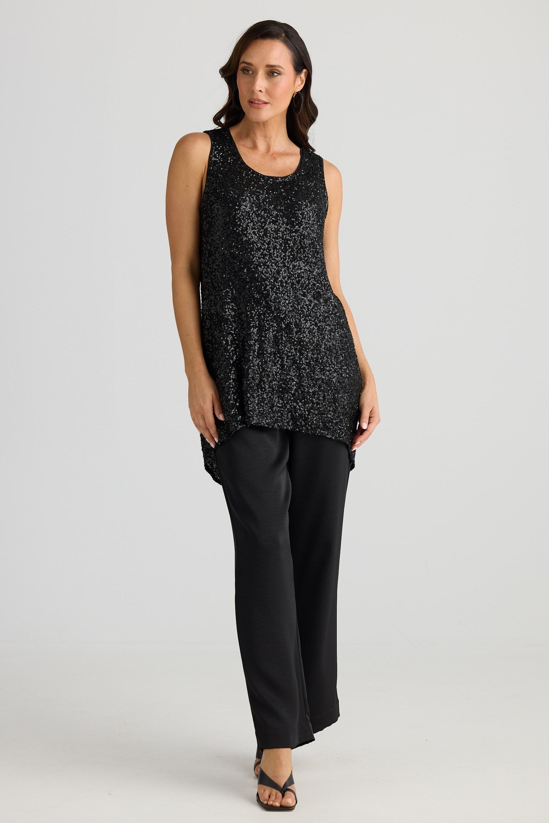 Woman wearing a black sequin top and black pants on a white background
