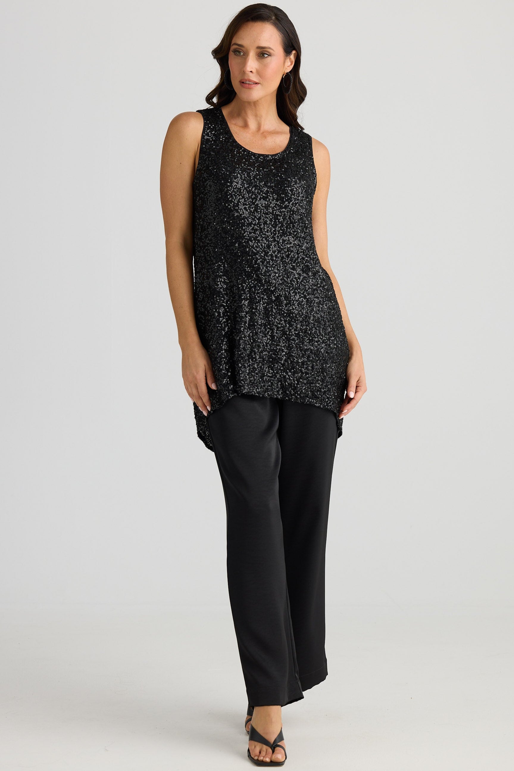 Woman wearing a black sequin top and black pants on a white background