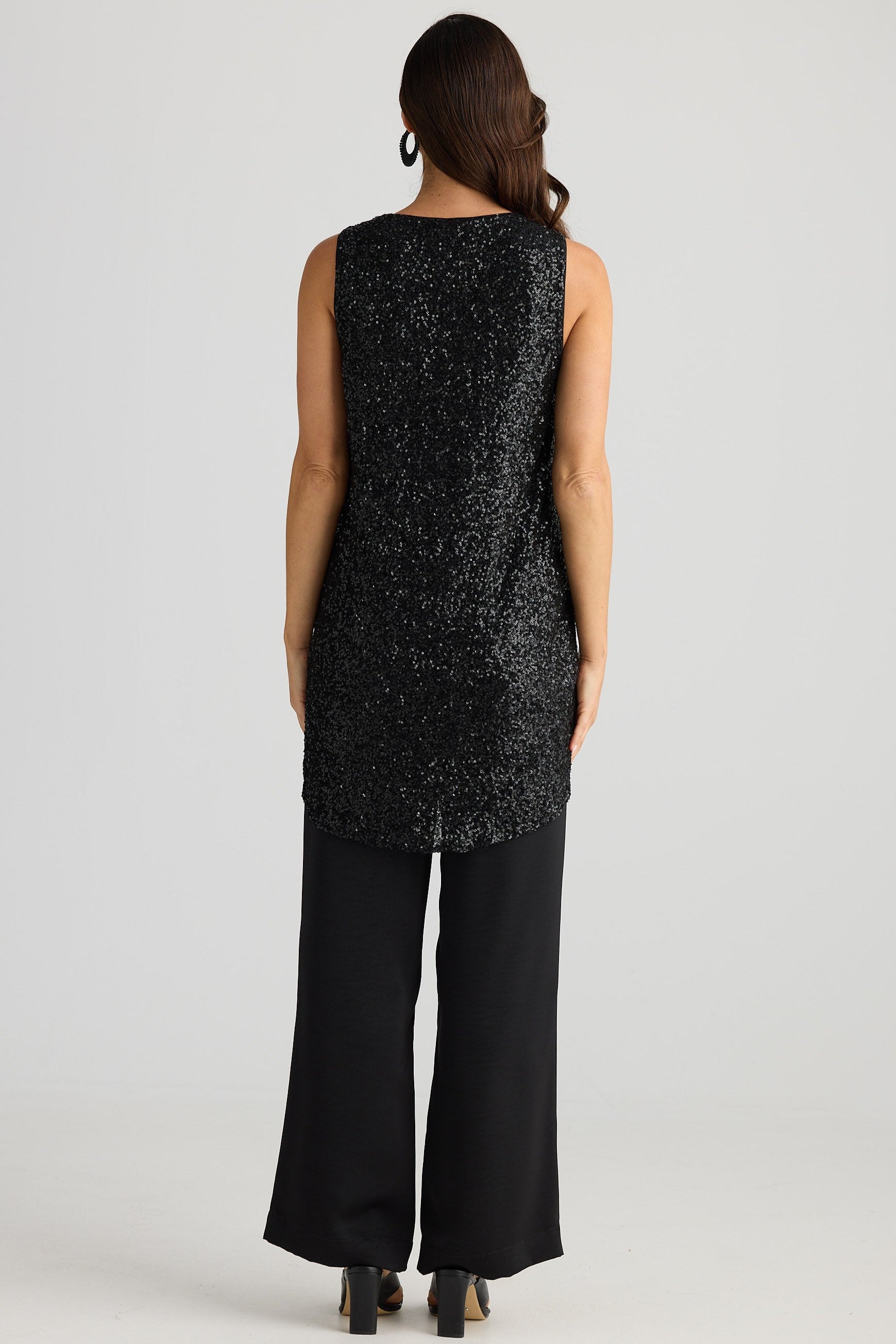 Woman wearing a black sleeveless top and pants on a white background