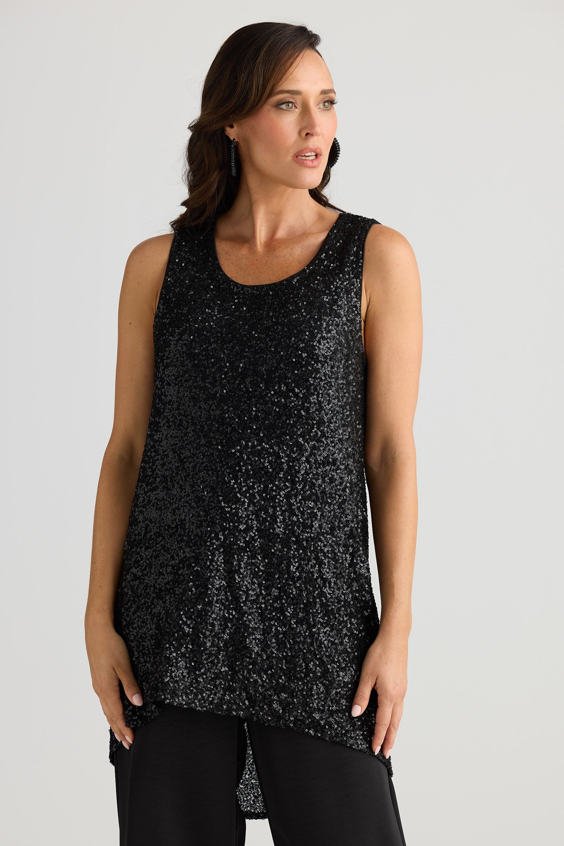 Woman wearing a black sleeveless top with a subtle pattern on a plain background