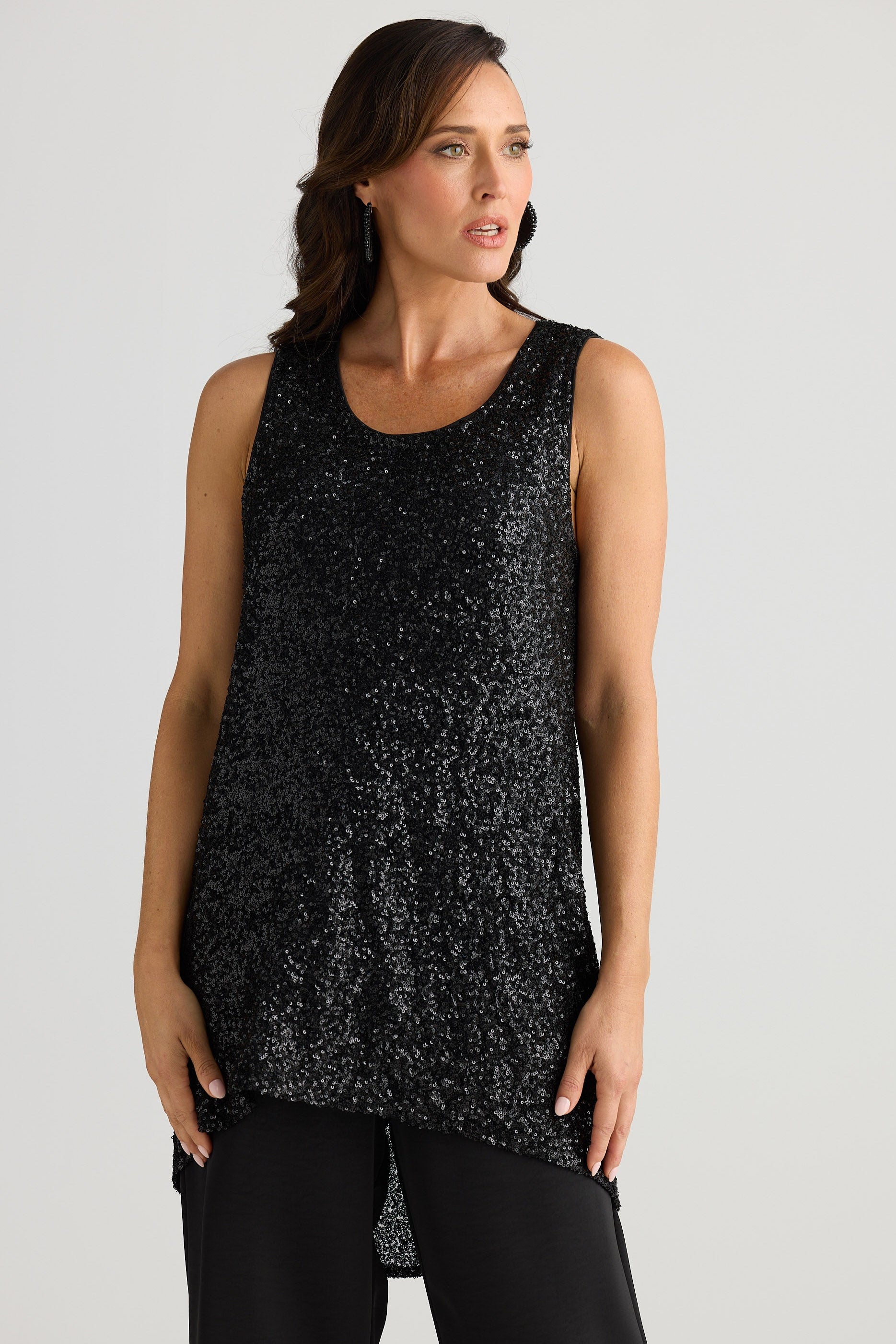 Woman wearing a black sleeveless top with a subtle pattern on a plain background