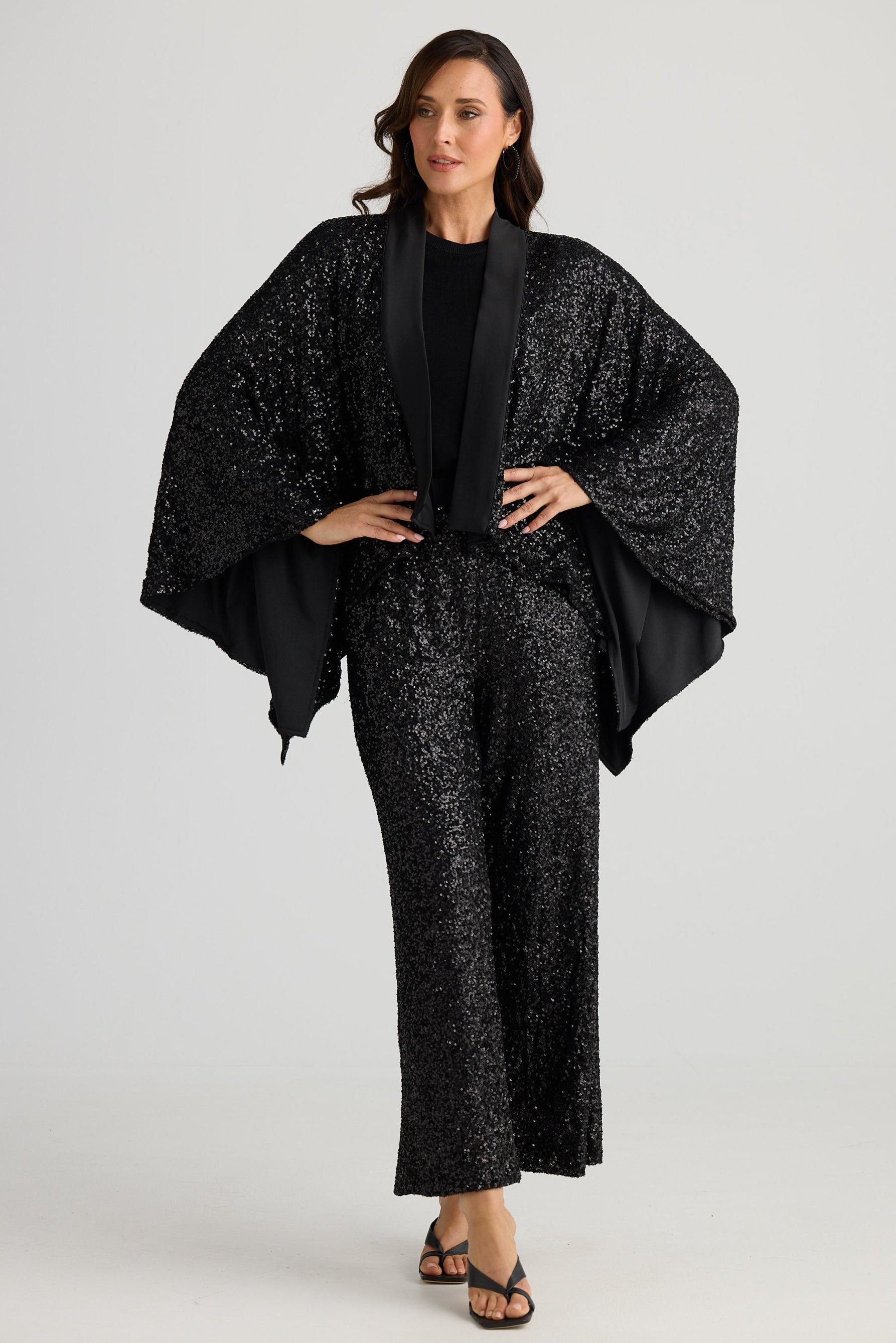 Woman wearing a black sequin outfit on a white background