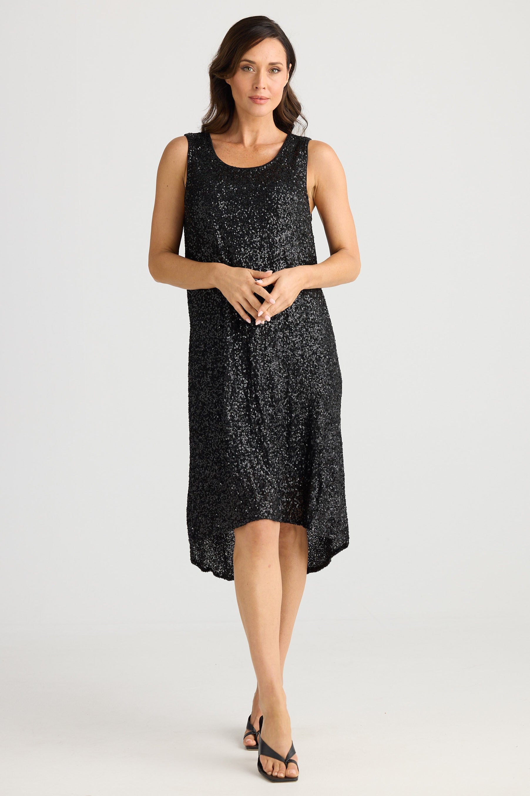 Woman wearing a black sleeveless dress with white patterns on a white background