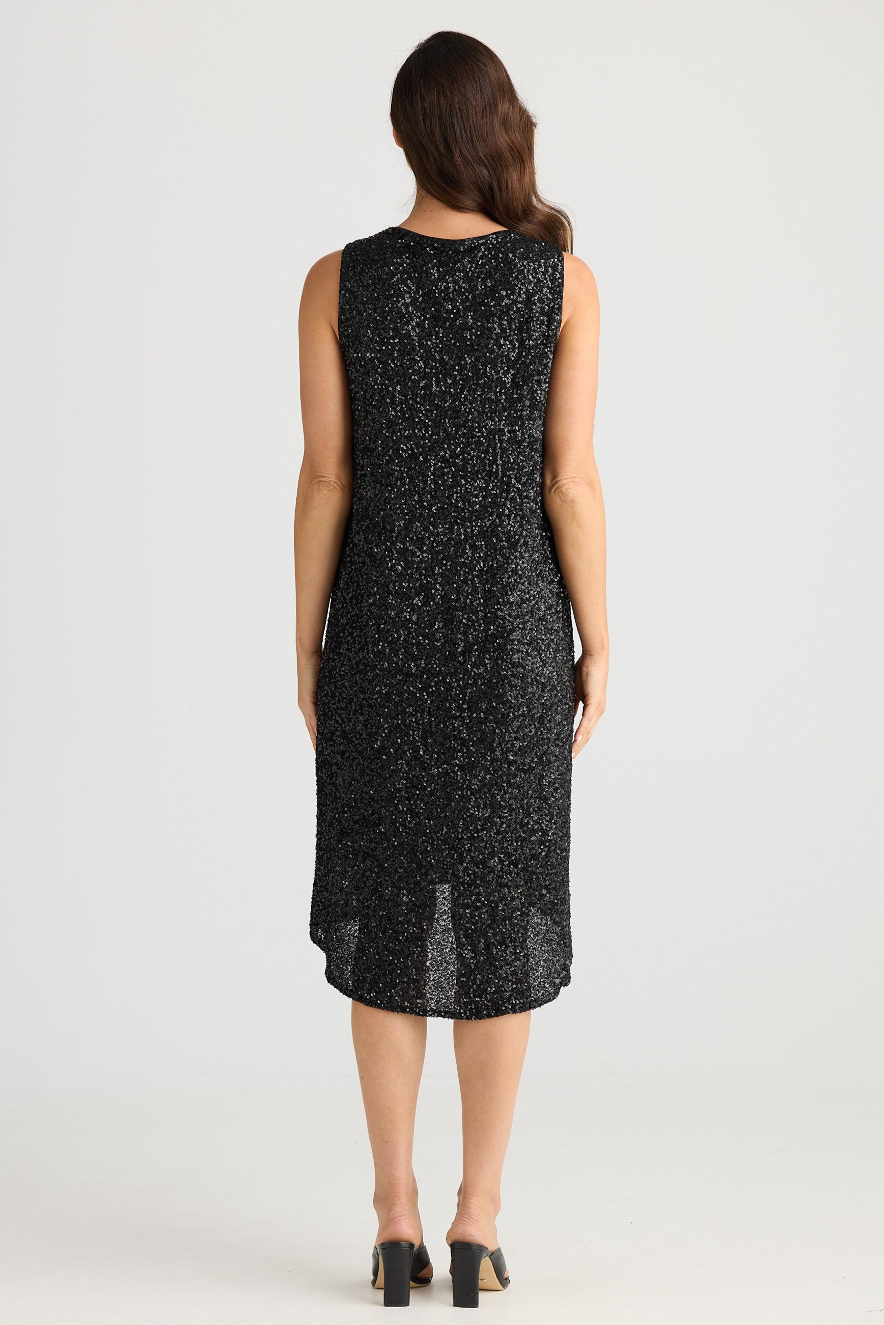 Woman wearing a black sleeveless dress with lace details on a white background