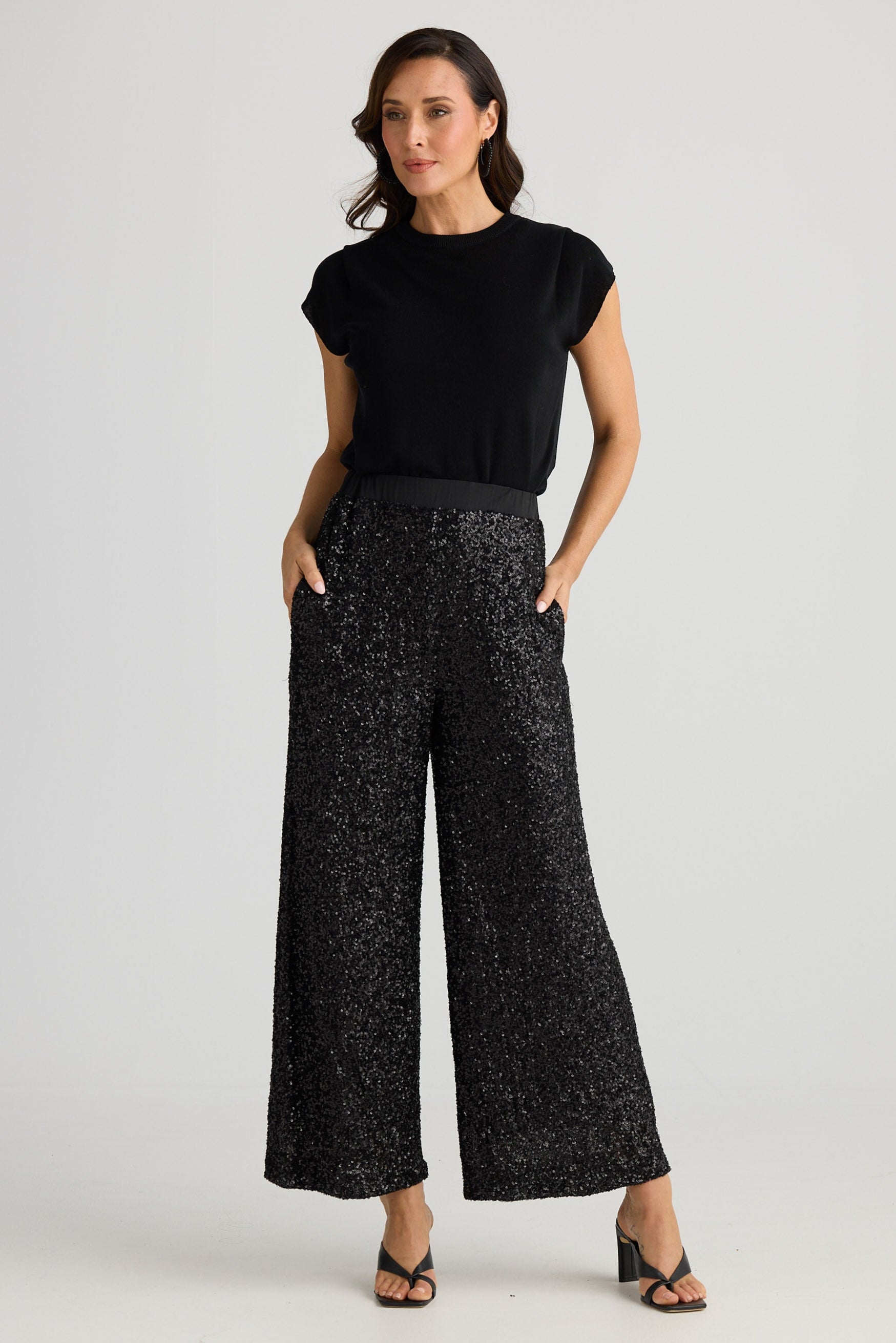 Woman wearing a black top and wide-leg pants on a white background