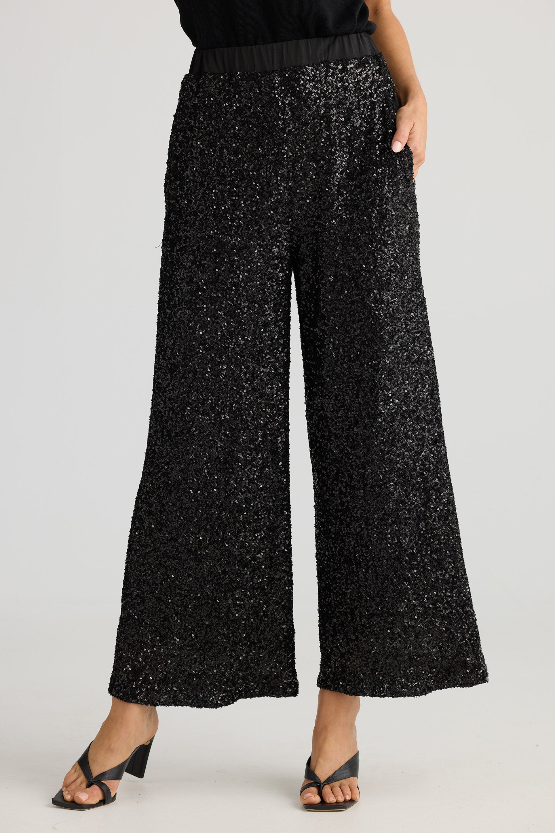 Black sequin pants worn by a person on a plain background