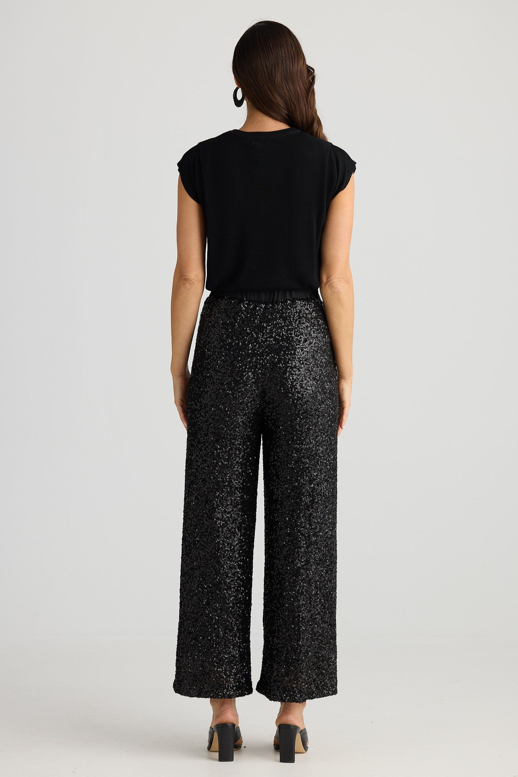 Woman wearing a black top and patterned pants on a white background