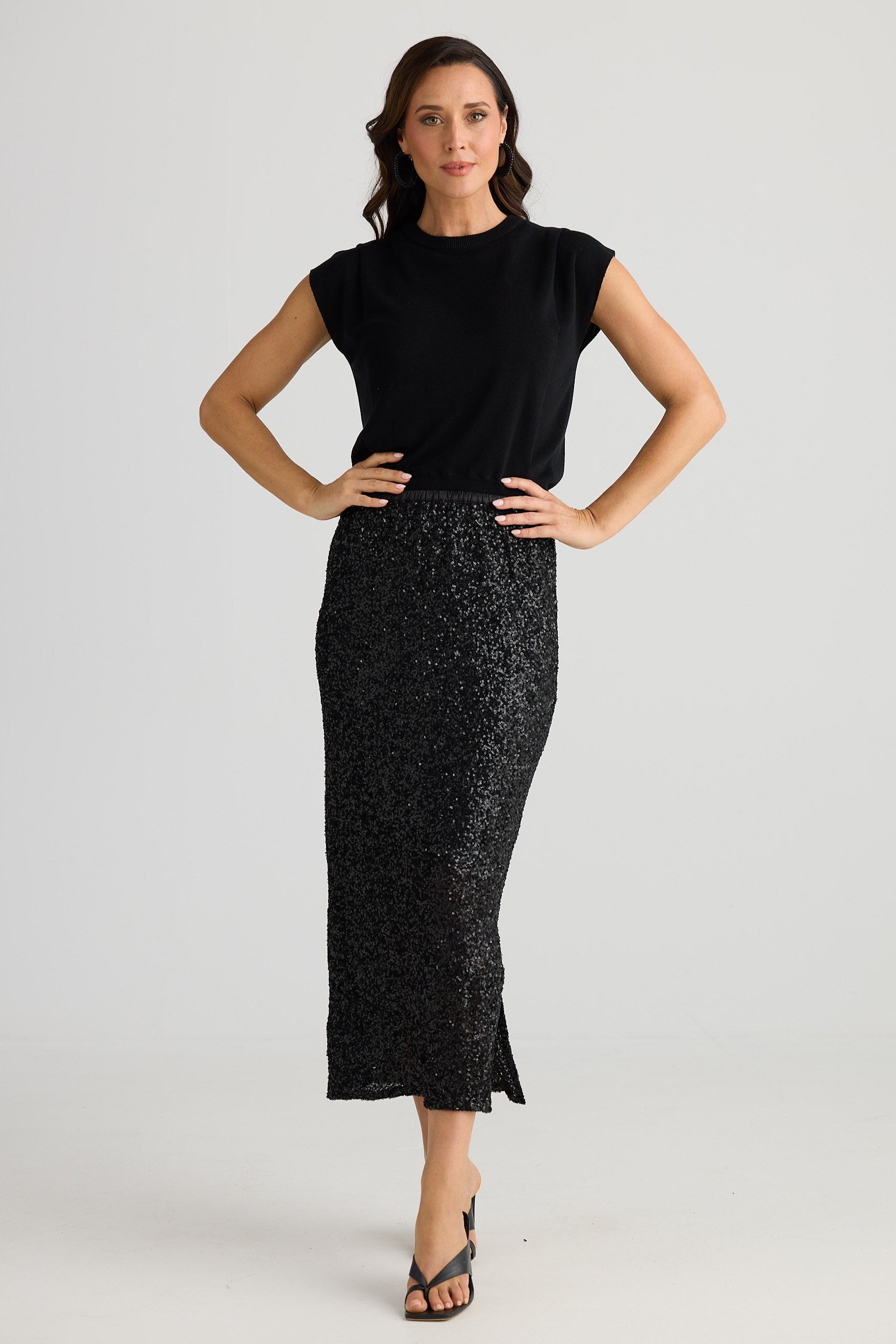 Woman wearing a black sleeveless top and black patterned skirt on a white background