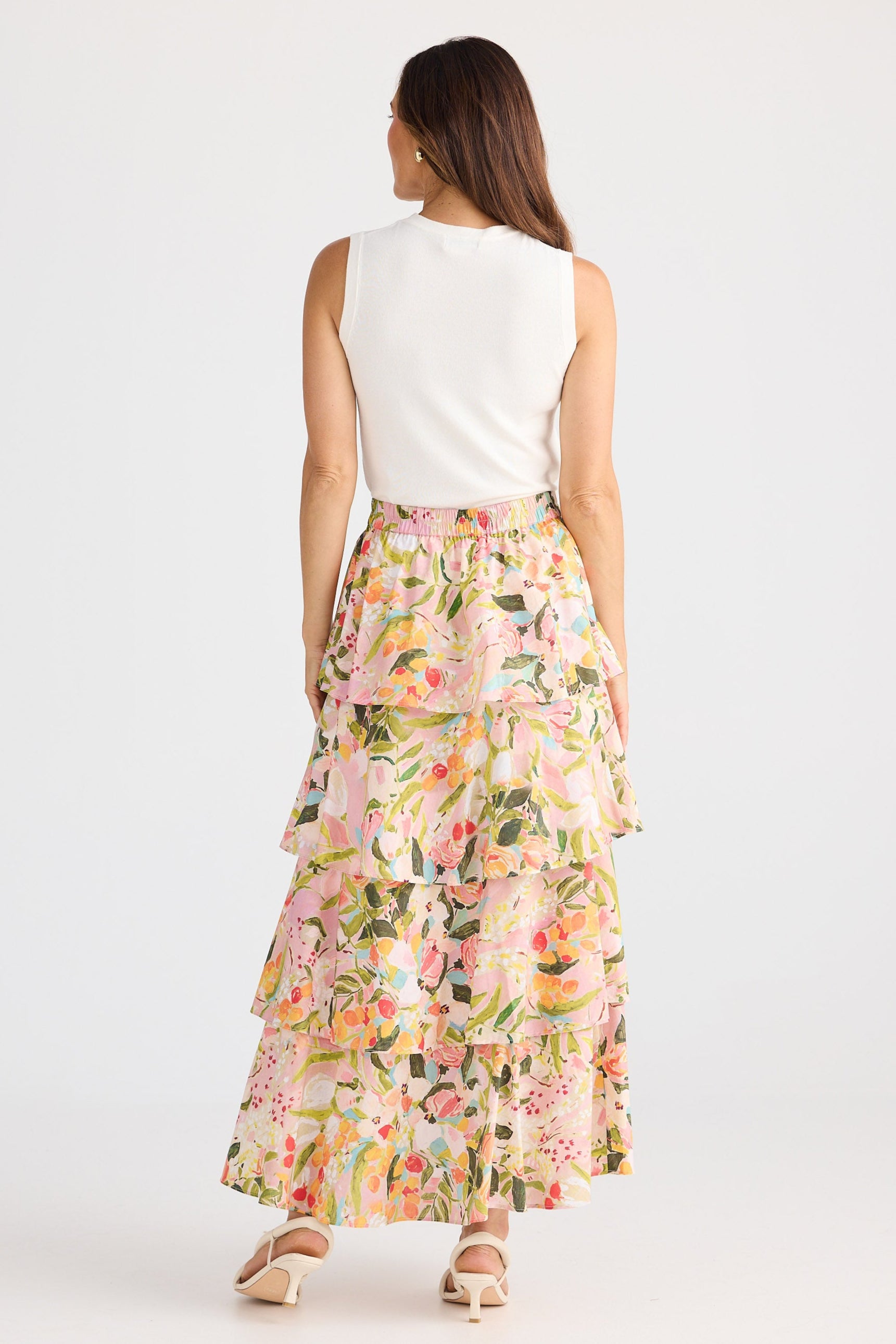 Woman wearing a floral skirt and white top on a white background