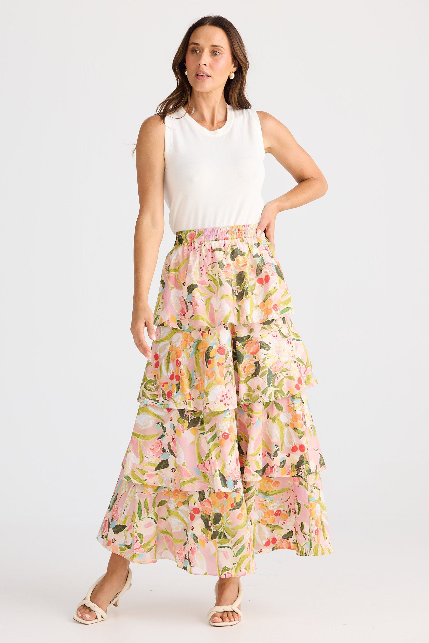 Woman wearing a white sleeveless top and floral skirt on a white background