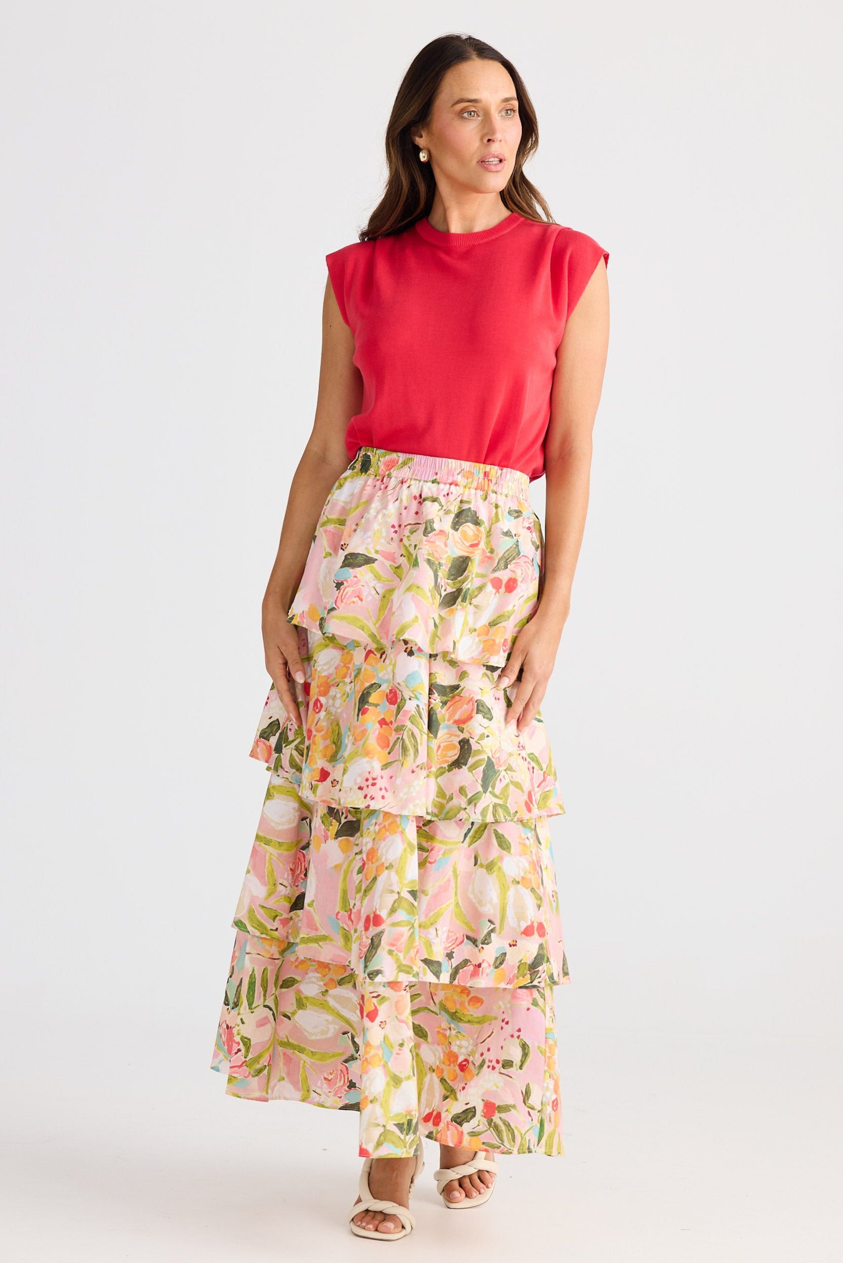 Woman wearing a red top and floral skirt on a white background