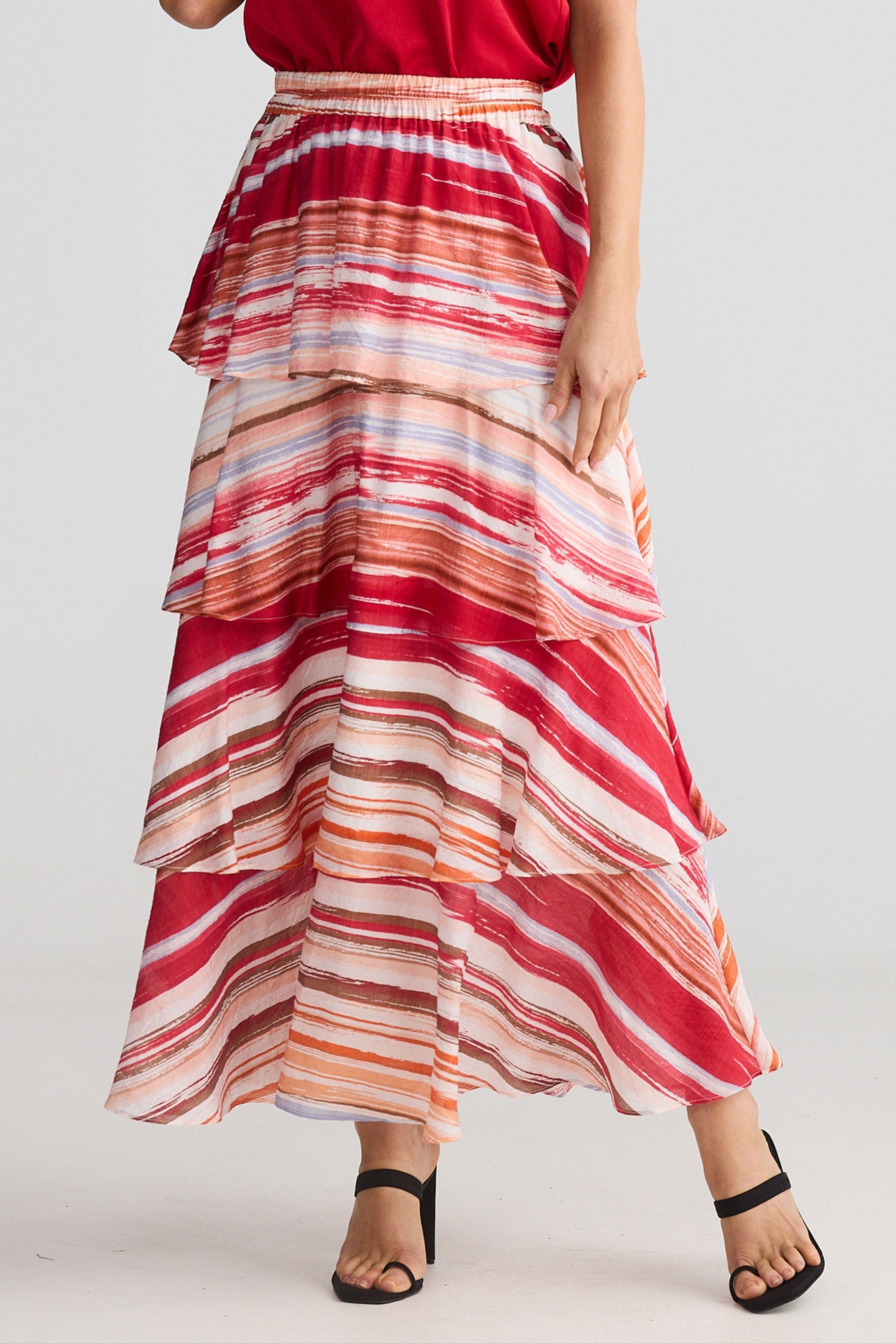 Person wearing a red top and colorful striped skirt on a white background