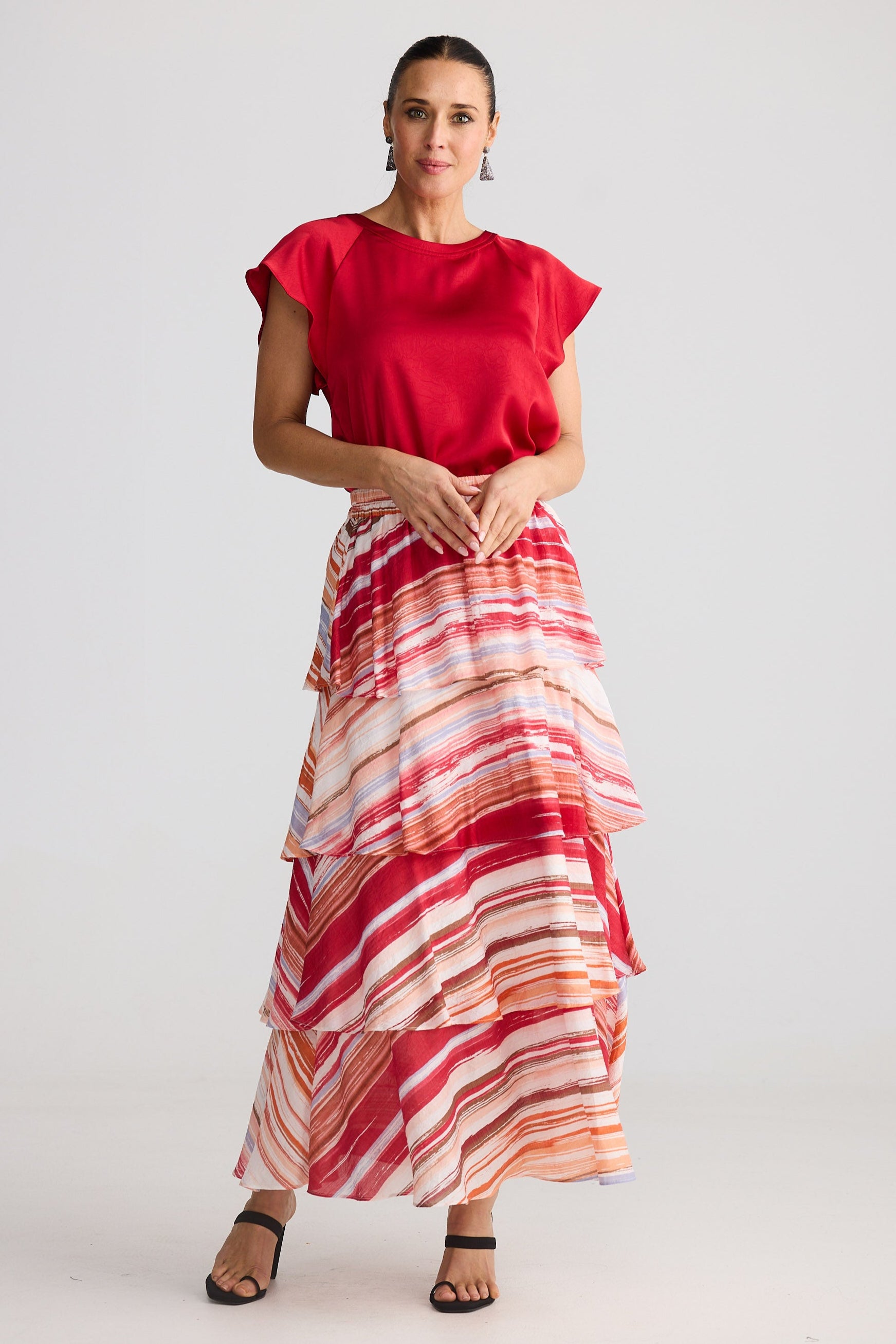 Woman wearing a red top and a long, multicolored skirt on a white background