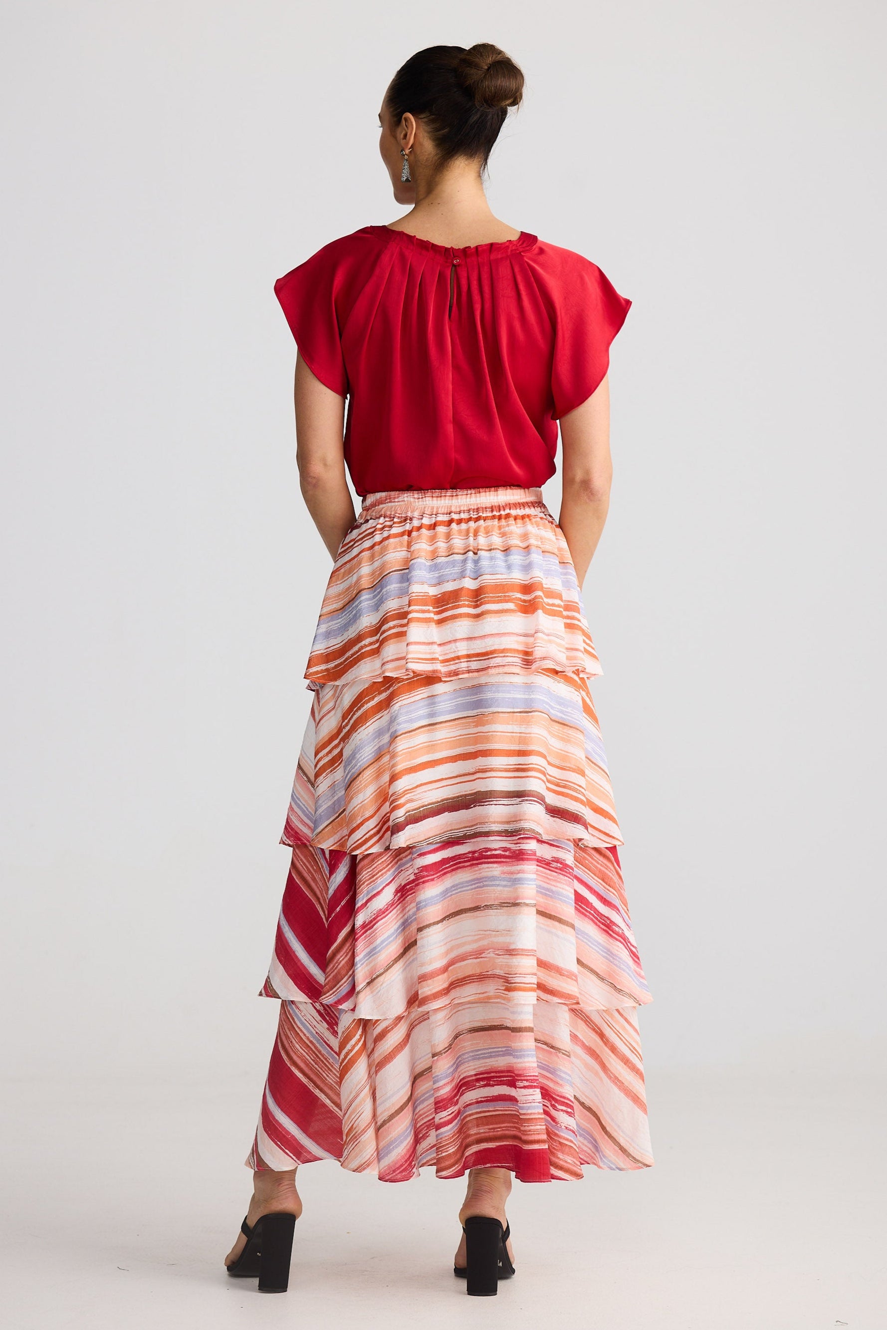 Woman wearing a red top and colorful striped skirt on a white background