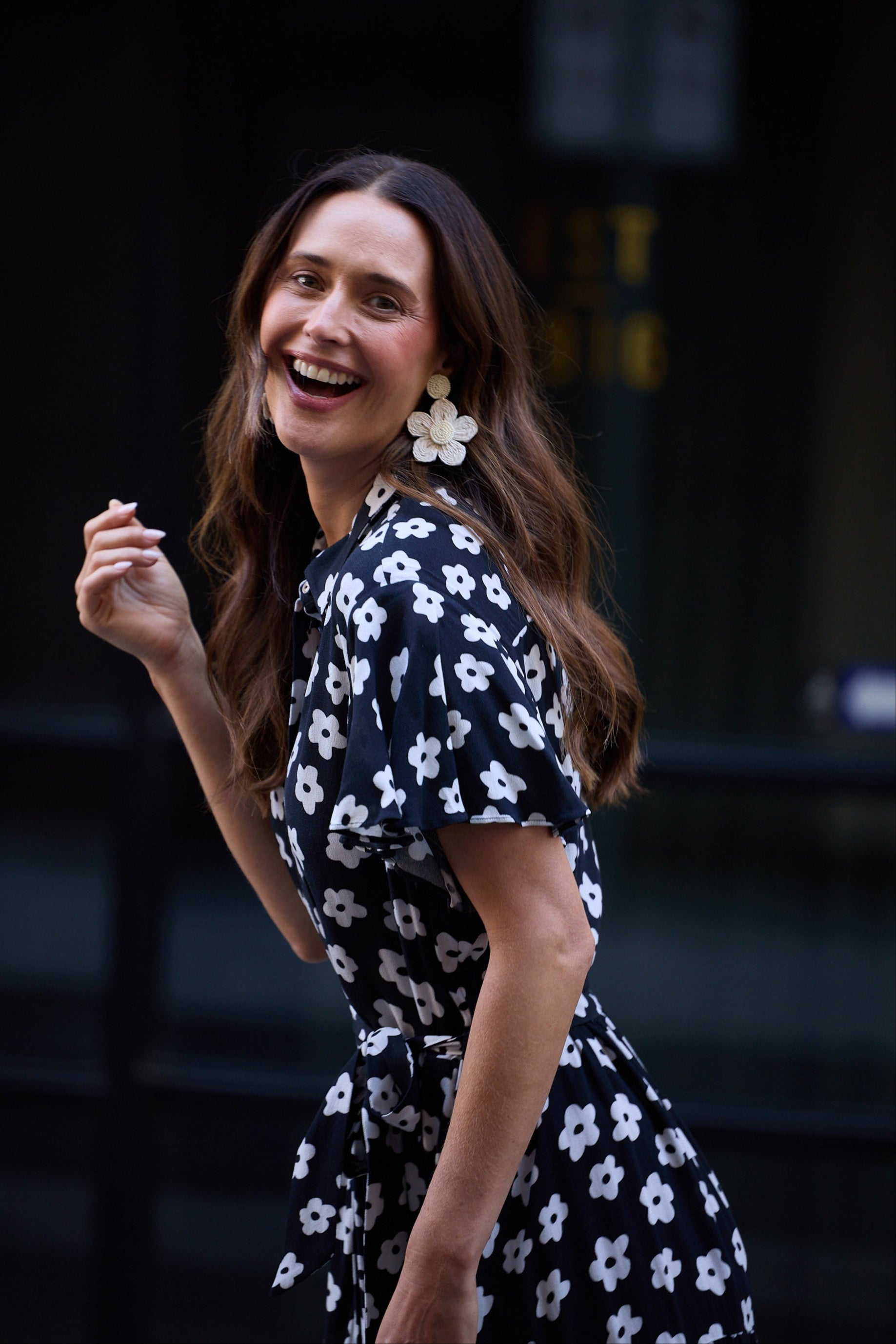 Woman in a navy floral dress laughing outdoors