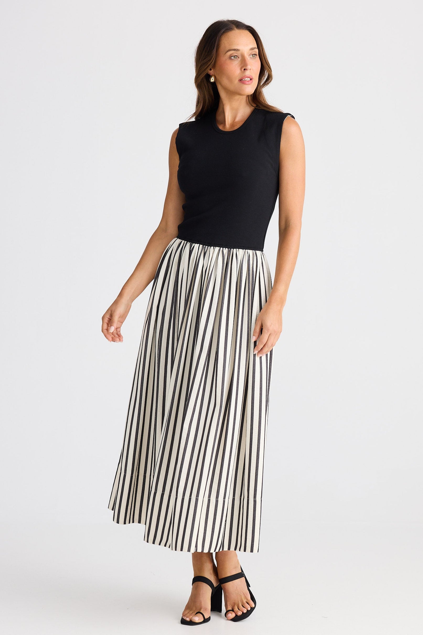 Woman wearing a dress with a black sleeveless top and striped skirt on a white background