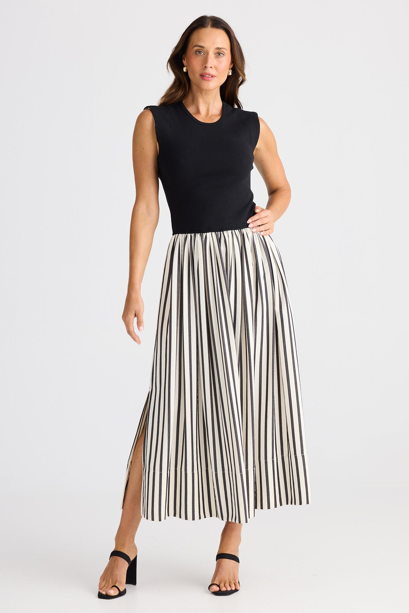 Woman wearing a dress with black sleeveless top and striped skirt on a white background
