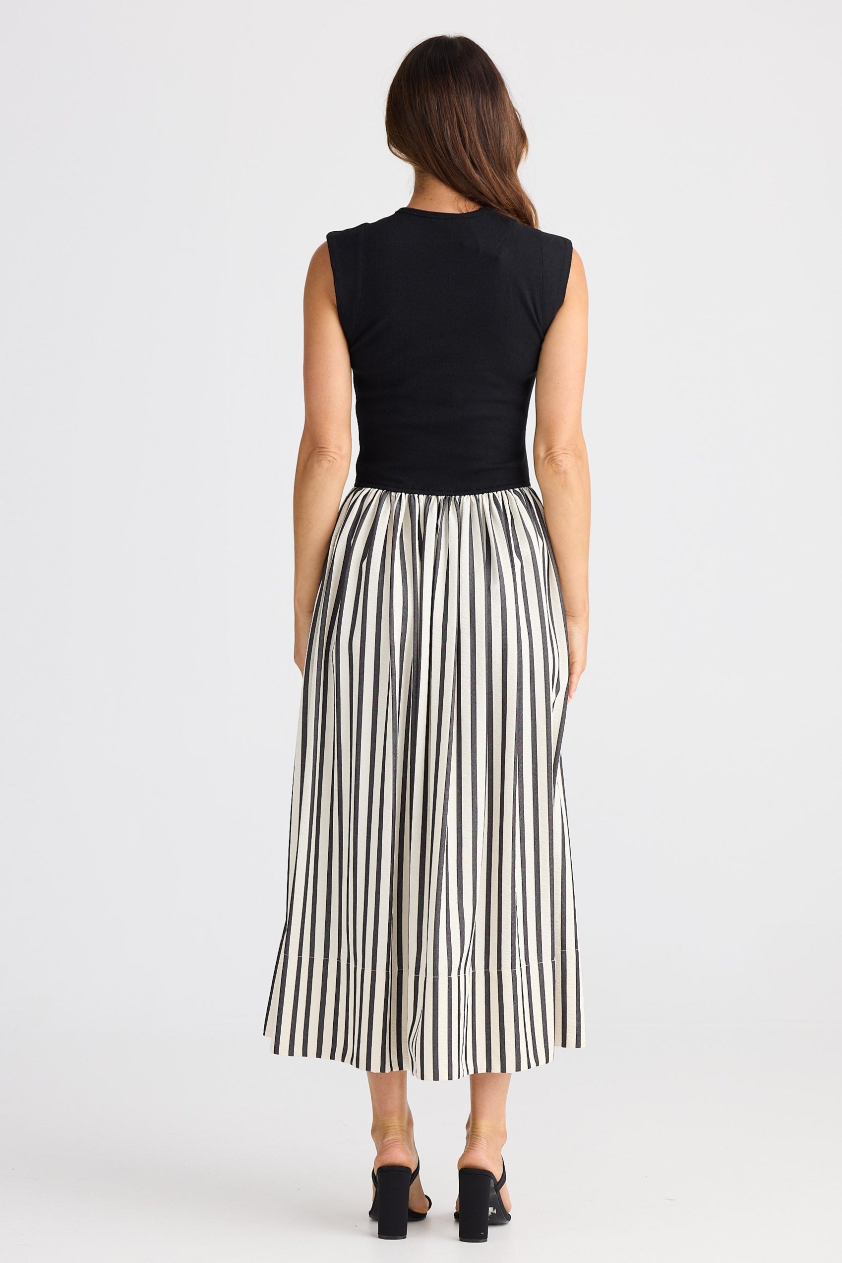 Woman wearing a dress with a black top and striped skirt on a white background