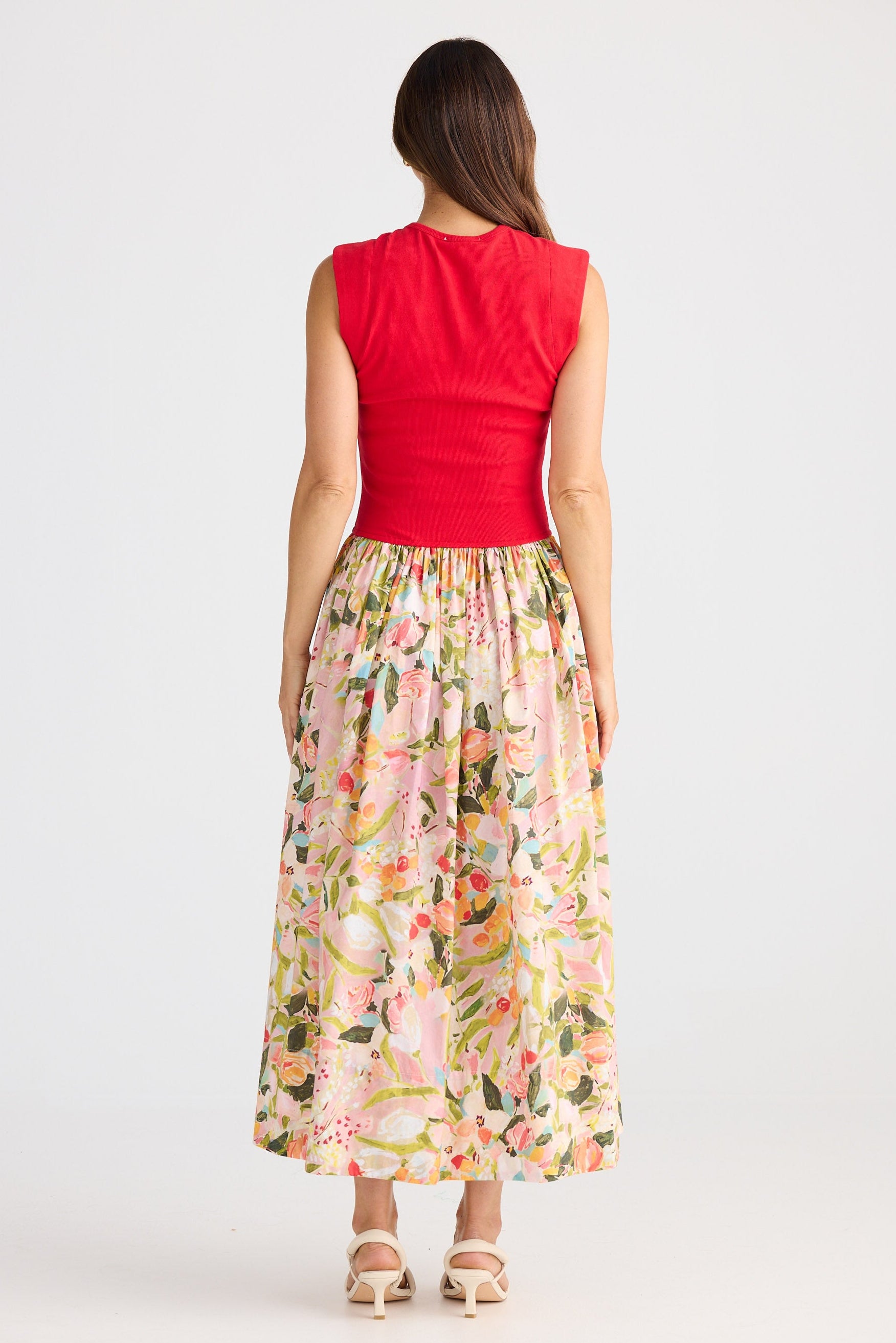 Woman wearing a dress with a red top and floral skirt on a white background