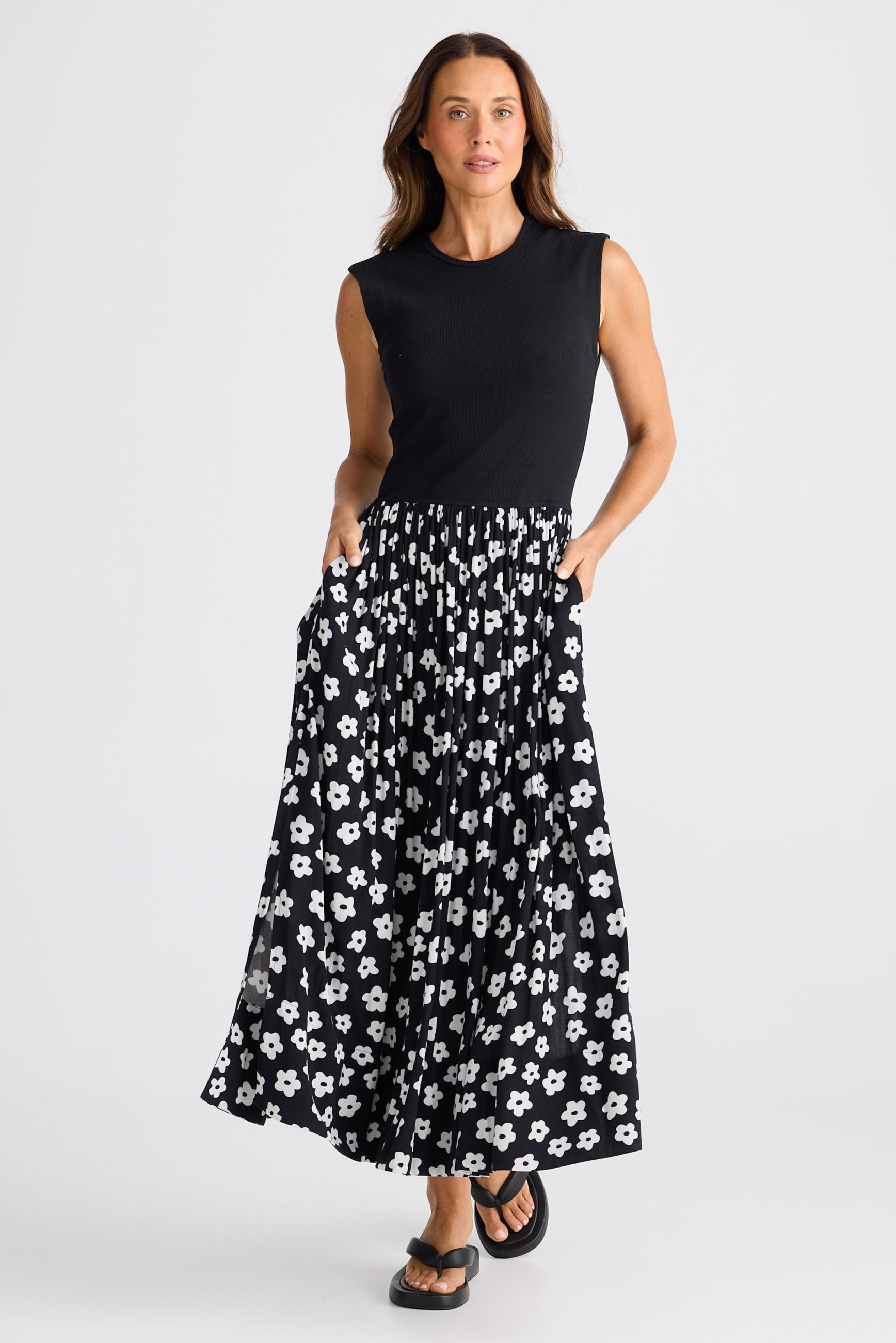 Woman wearing a dress with black sleeveless top and black floral skirt on a white background