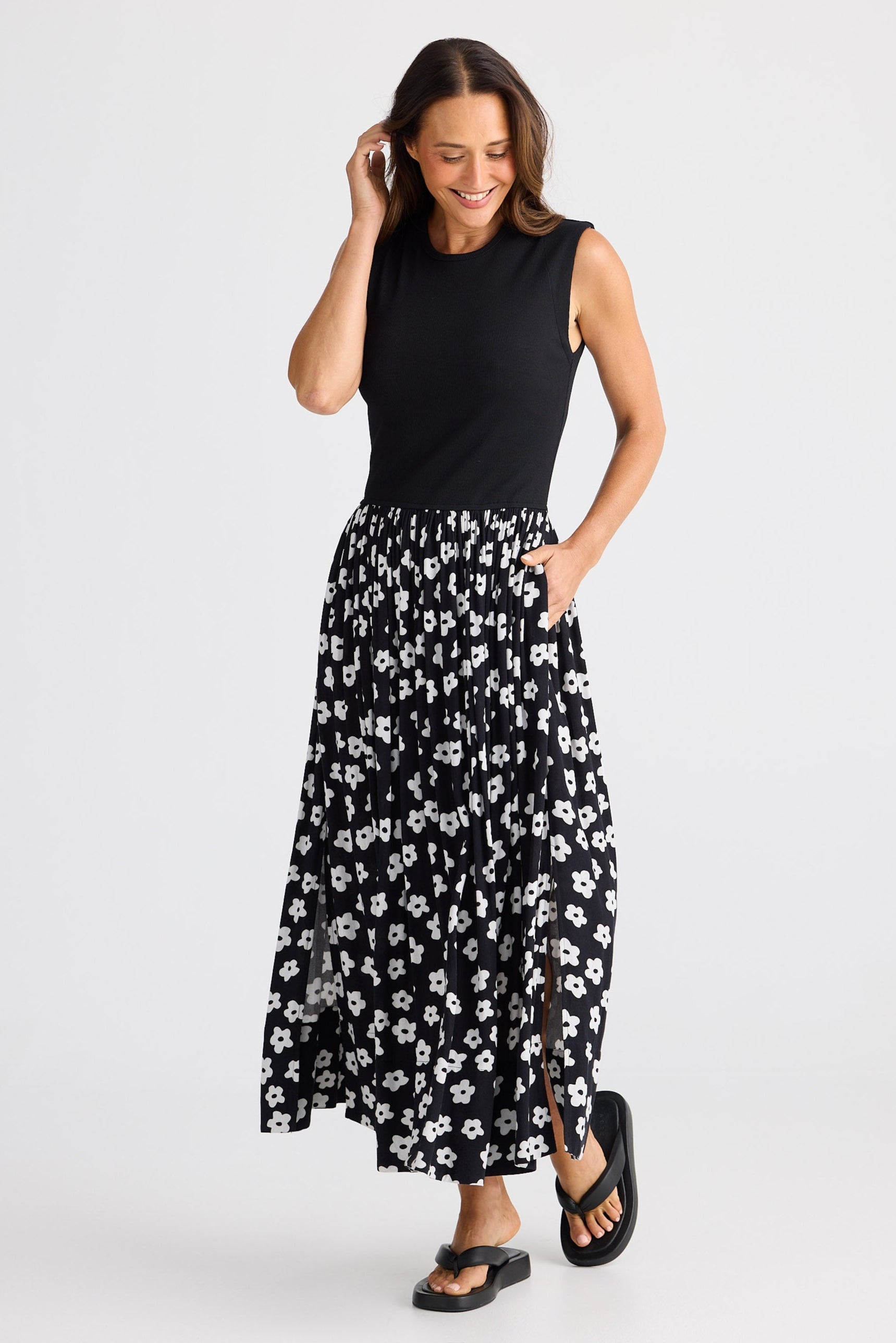 Woman wearing a dress with black sleeveless top and floral skirt on a white background