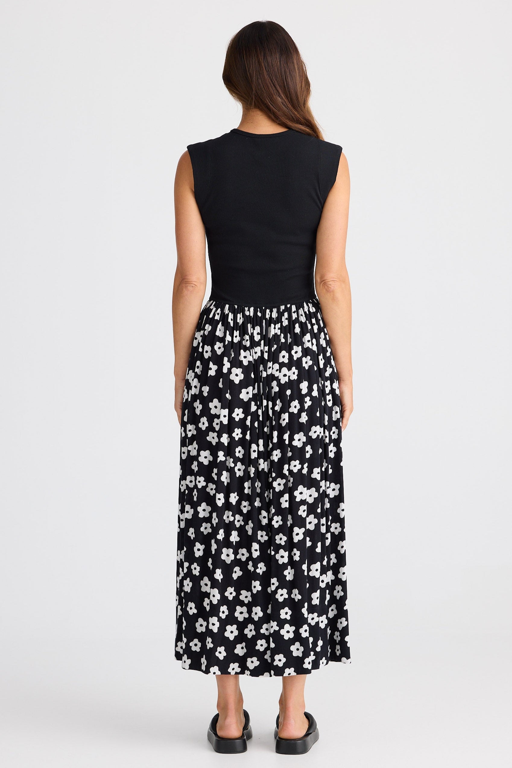 Woman wearing a dress with black sleeveless top and floral skirt on a white background