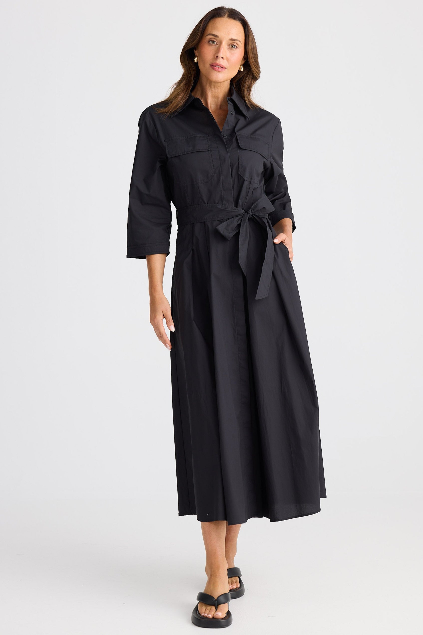 Woman wearing a black dress with waist tie on a white background