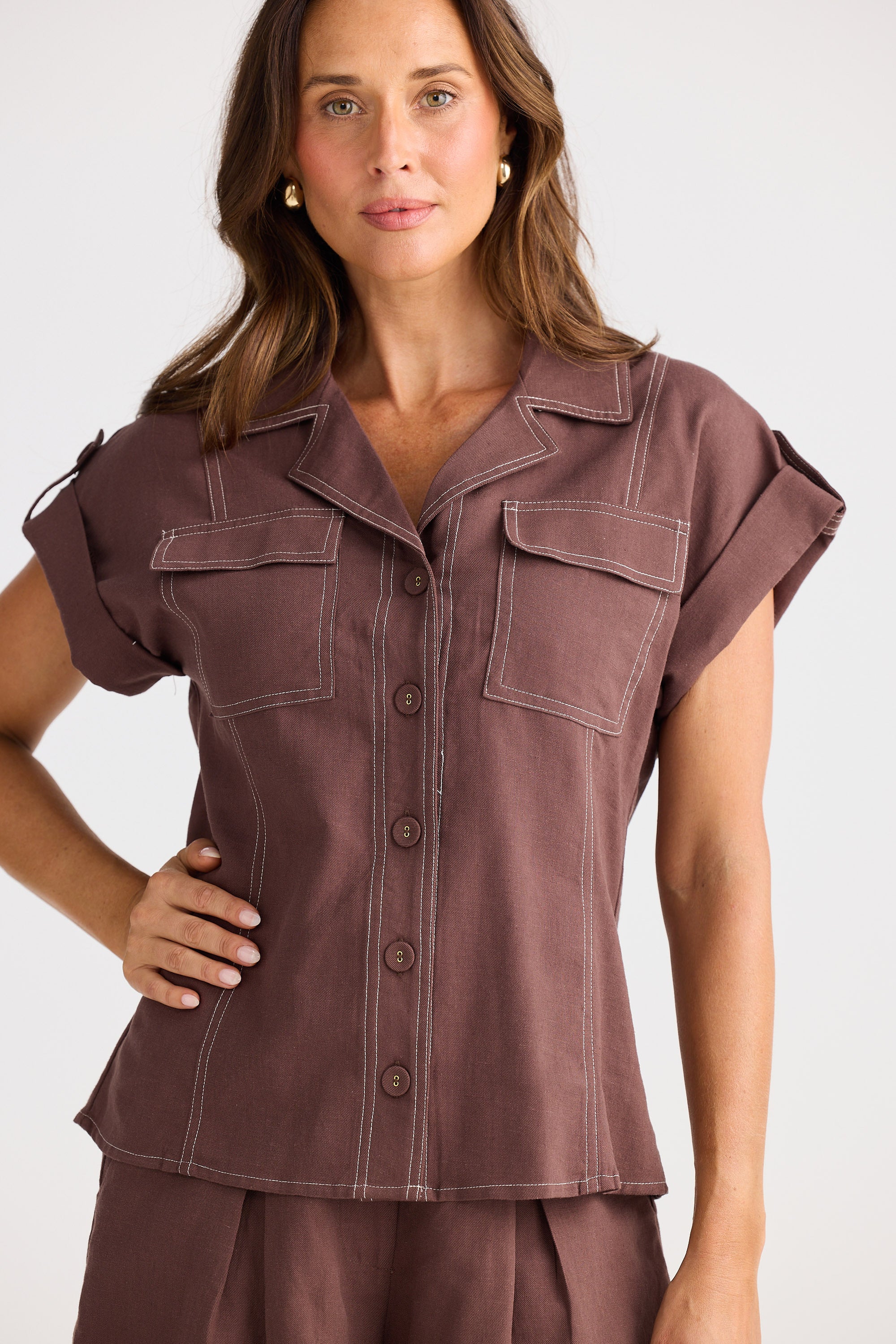 Woman wearing a brown shirt with rolled-up sleeves on a white background