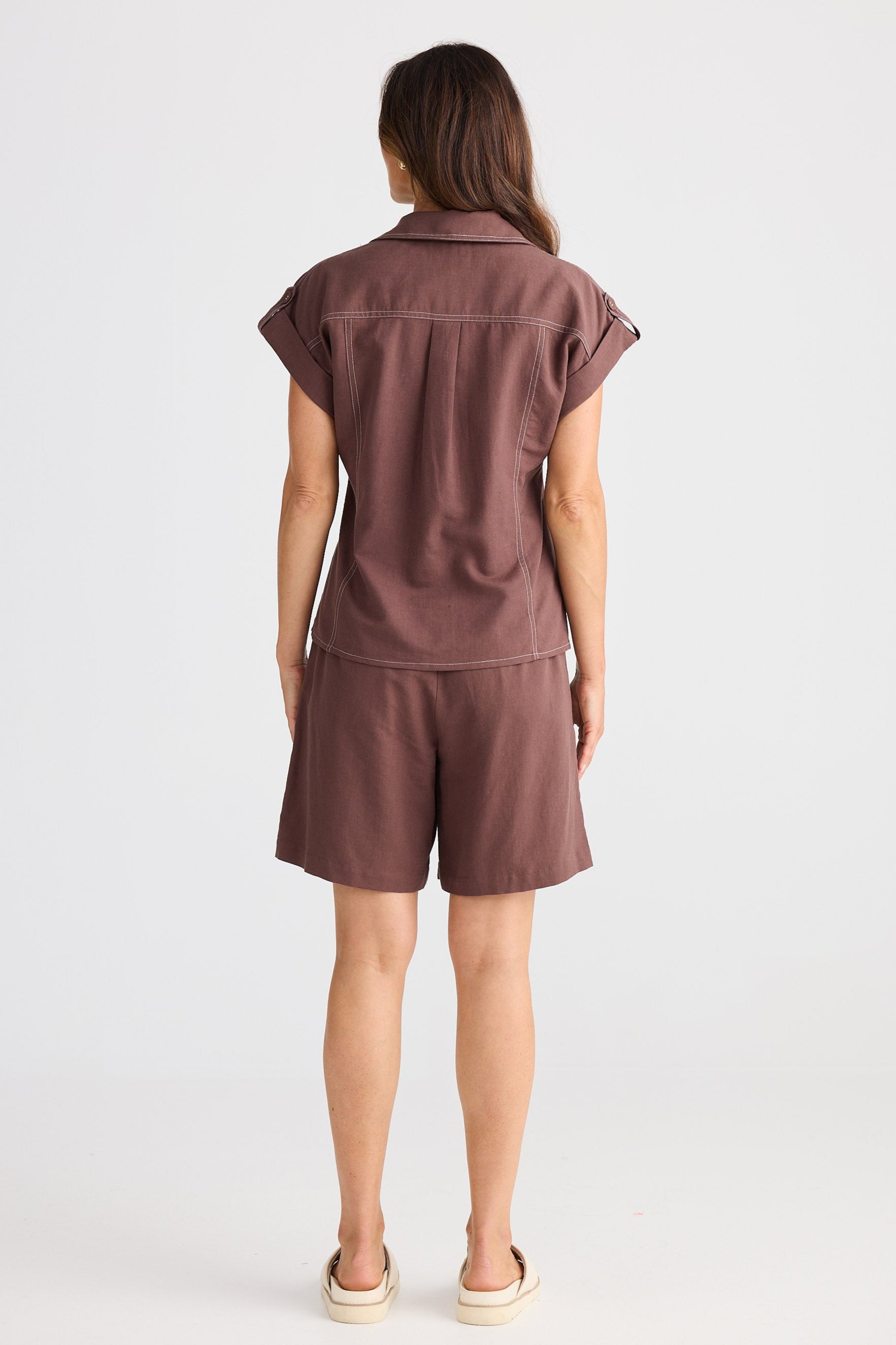 Person wearing a brown sleeveless top and shorts set on a white background