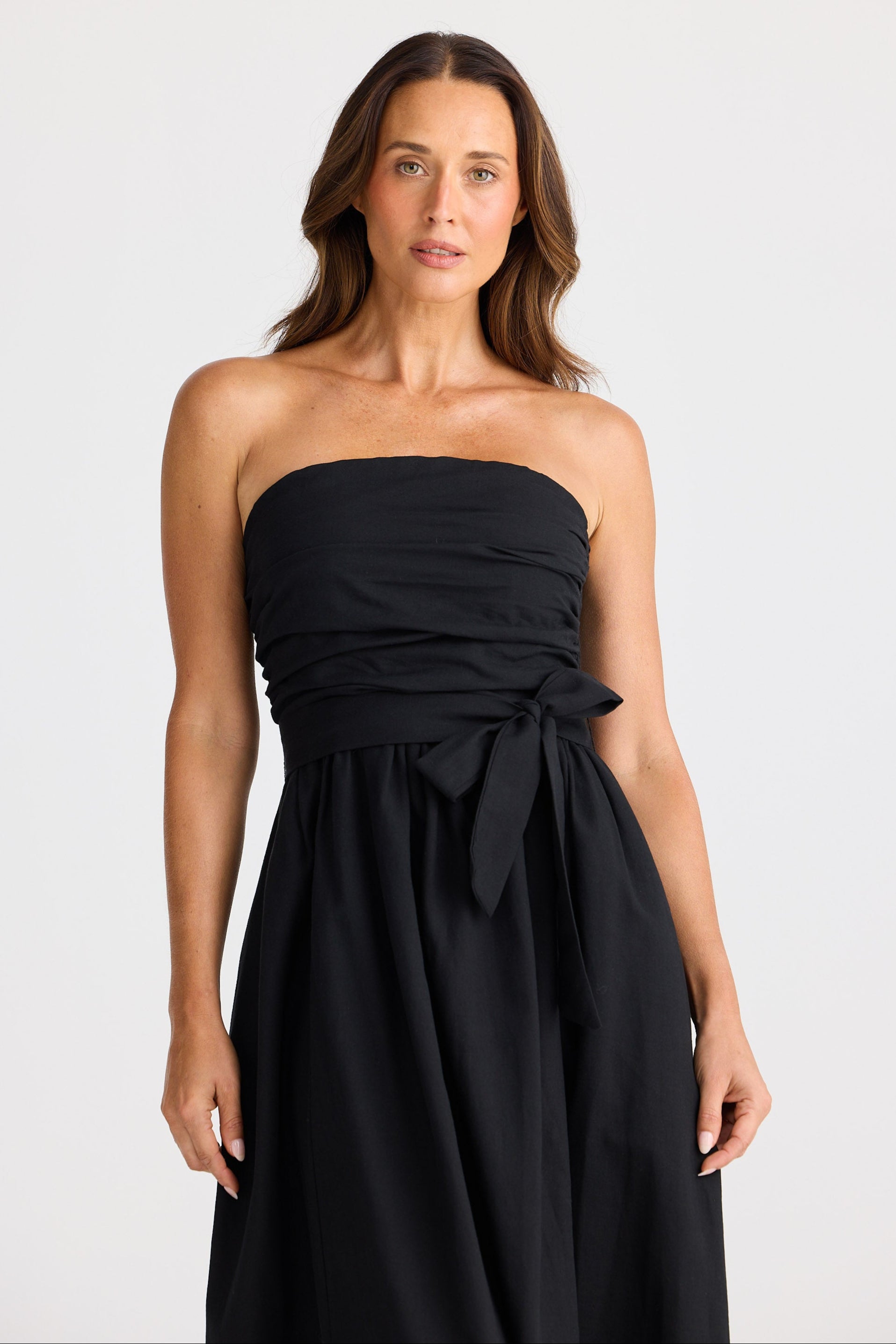 Woman wearing a black strapless dress on a white background