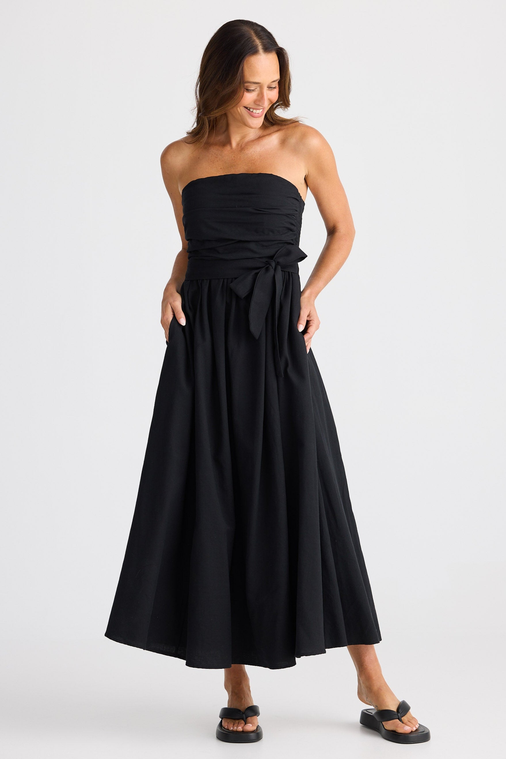 Woman wearing a black strapless dress on a white background