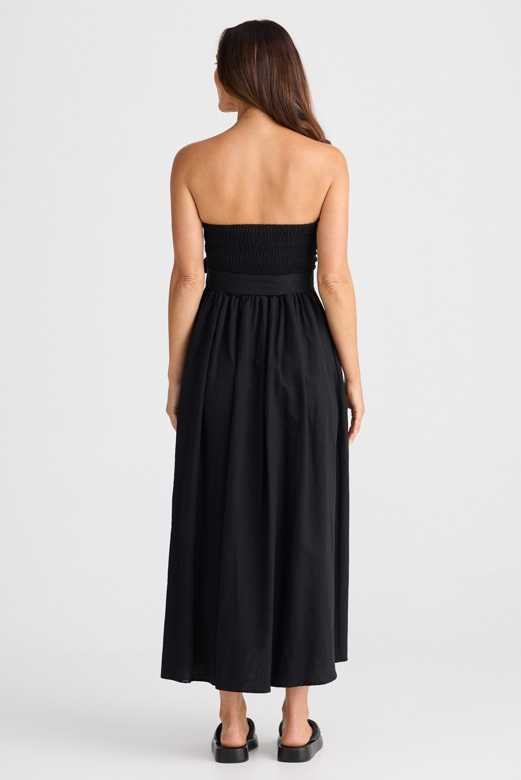 Woman wearing a black strapless dress on a white background