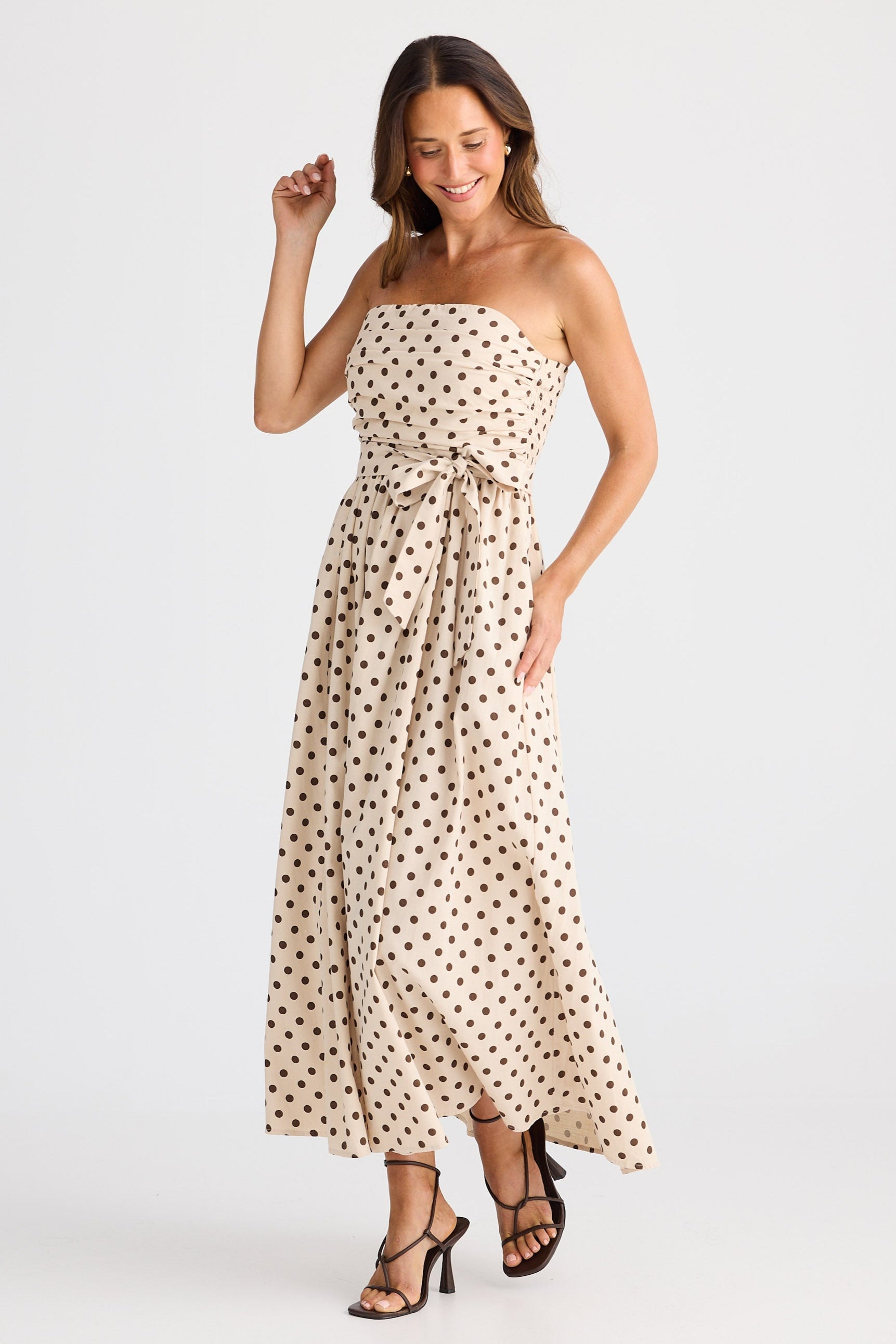 Woman wearing a strapless polka dot dress on a white background