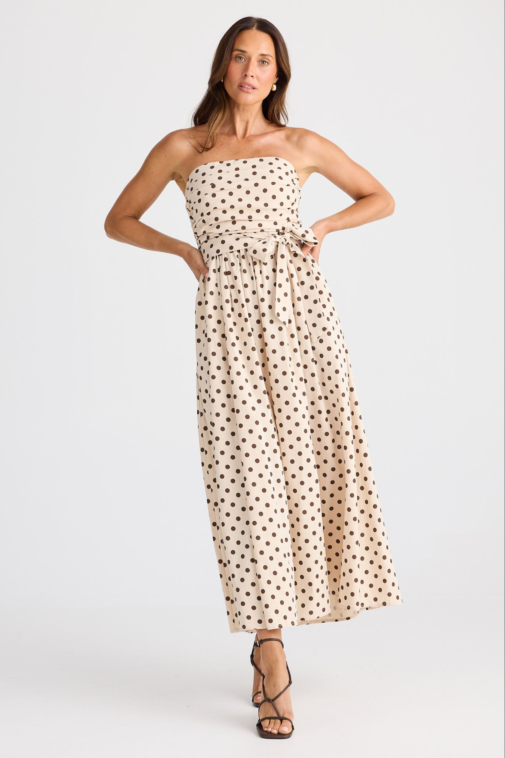 Woman wearing a strapless polka dot dress on a white background