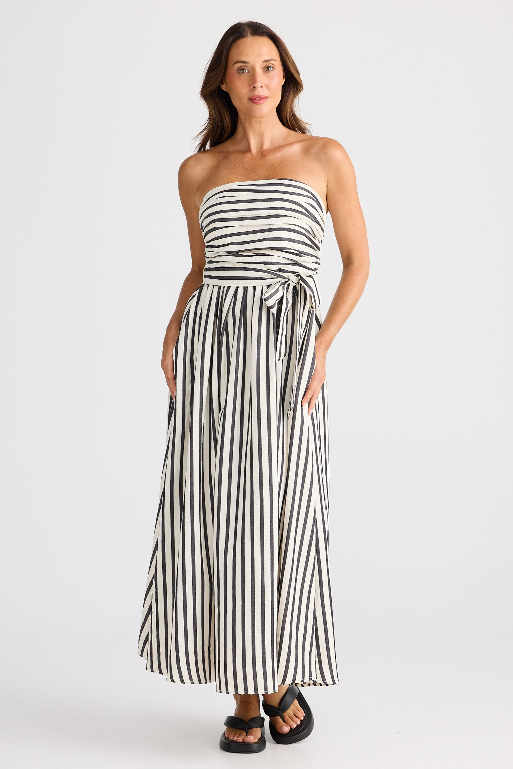 Woman wearing a black and white striped strapless dress on a white background