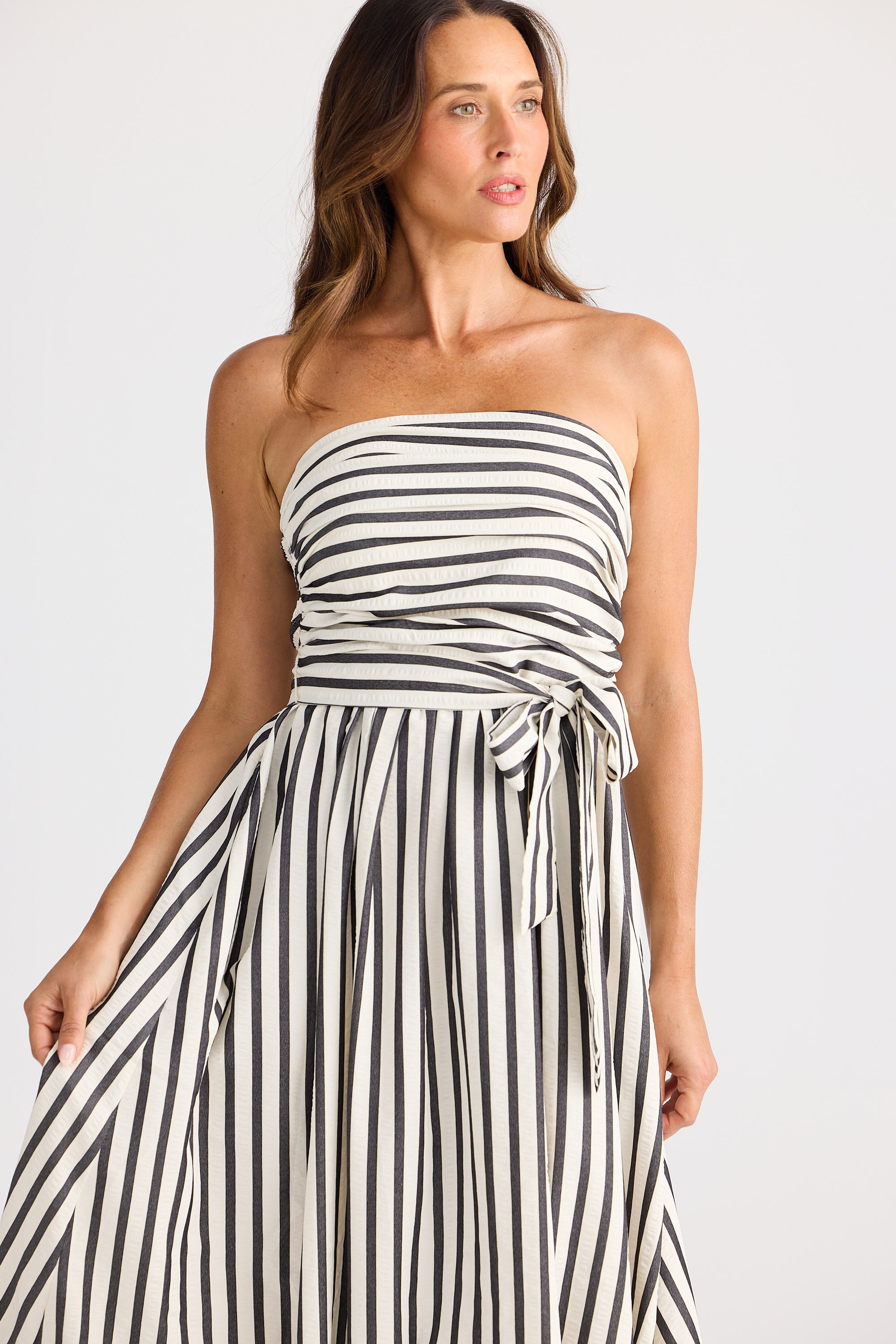 Woman wearing a black and white striped strapless dress on a white background