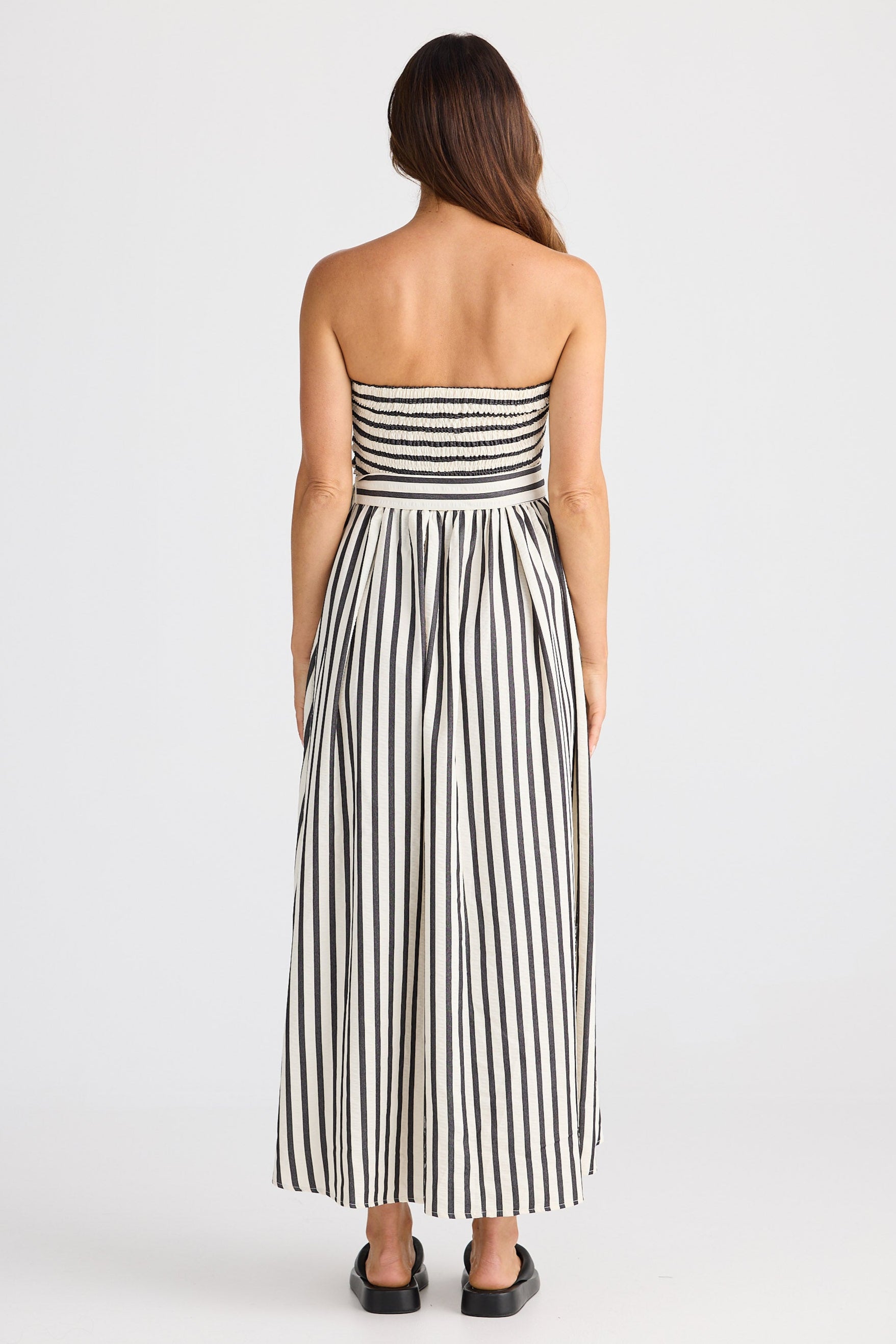 Woman wearing a strapless black and white striped dress on a white background