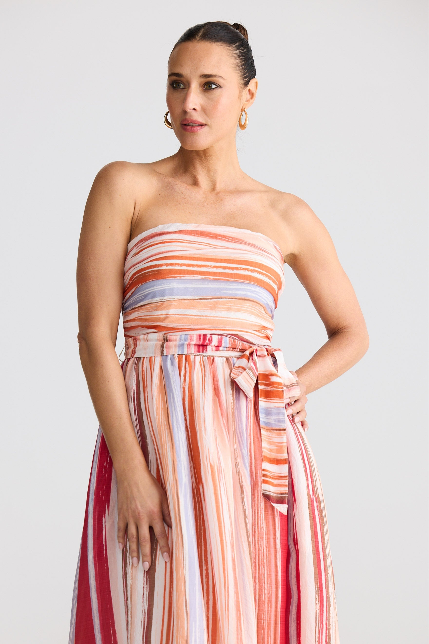 Woman wearing a strapless, multicolored dress against a plain background