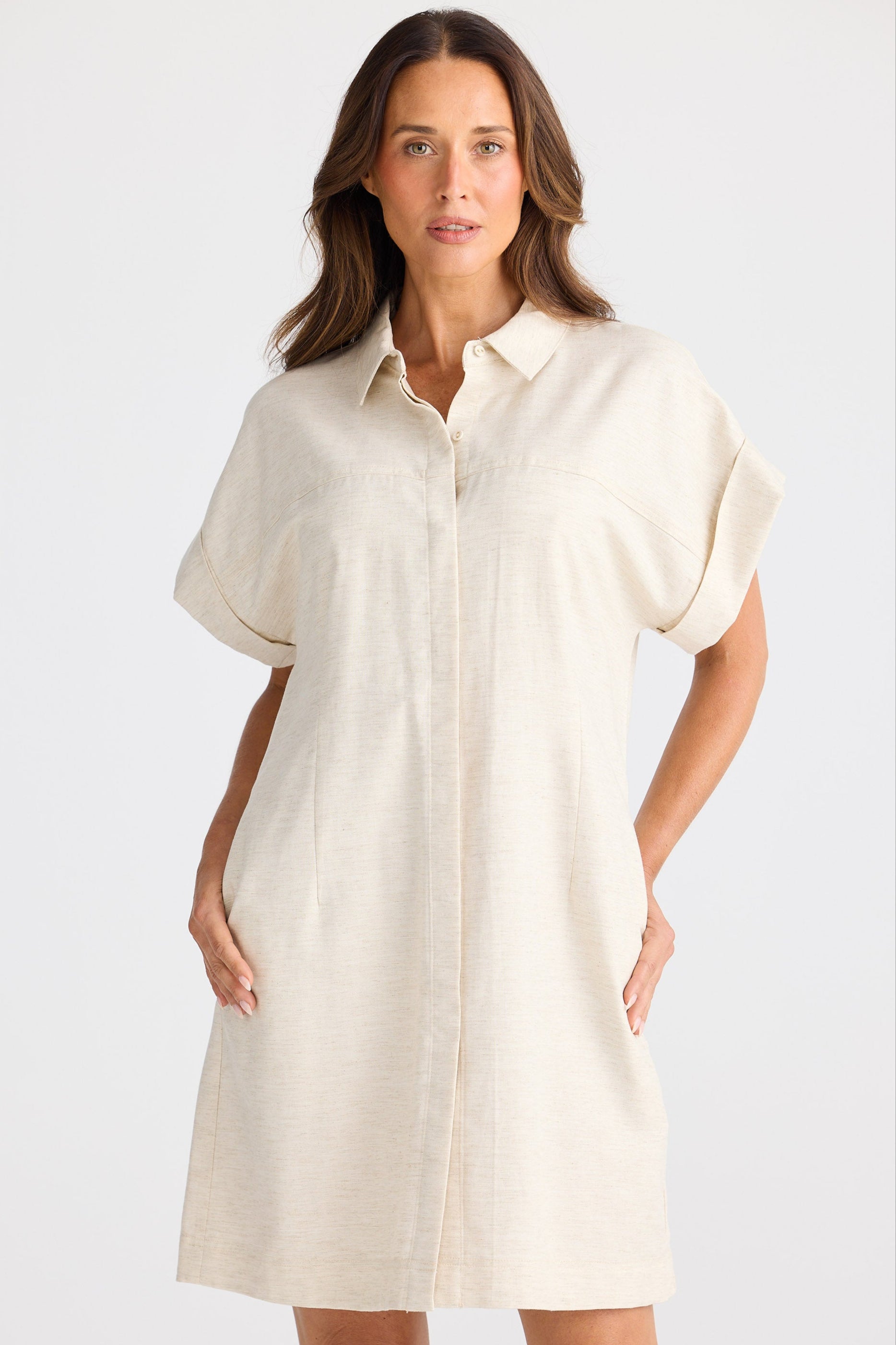 Woman wearing a beige shirt dress against a plain background