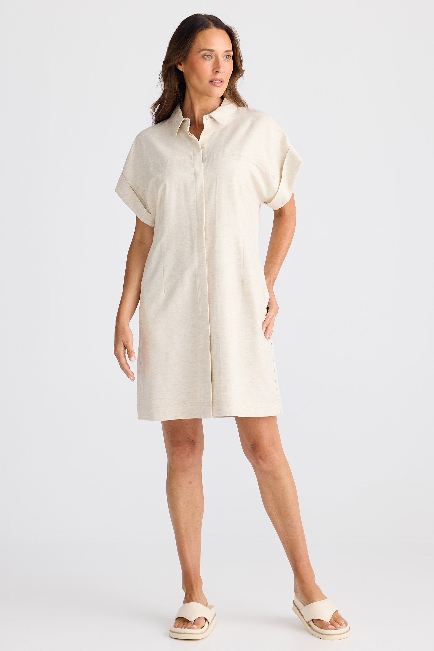 Woman wearing a cream-colored shirt dress on a white background
