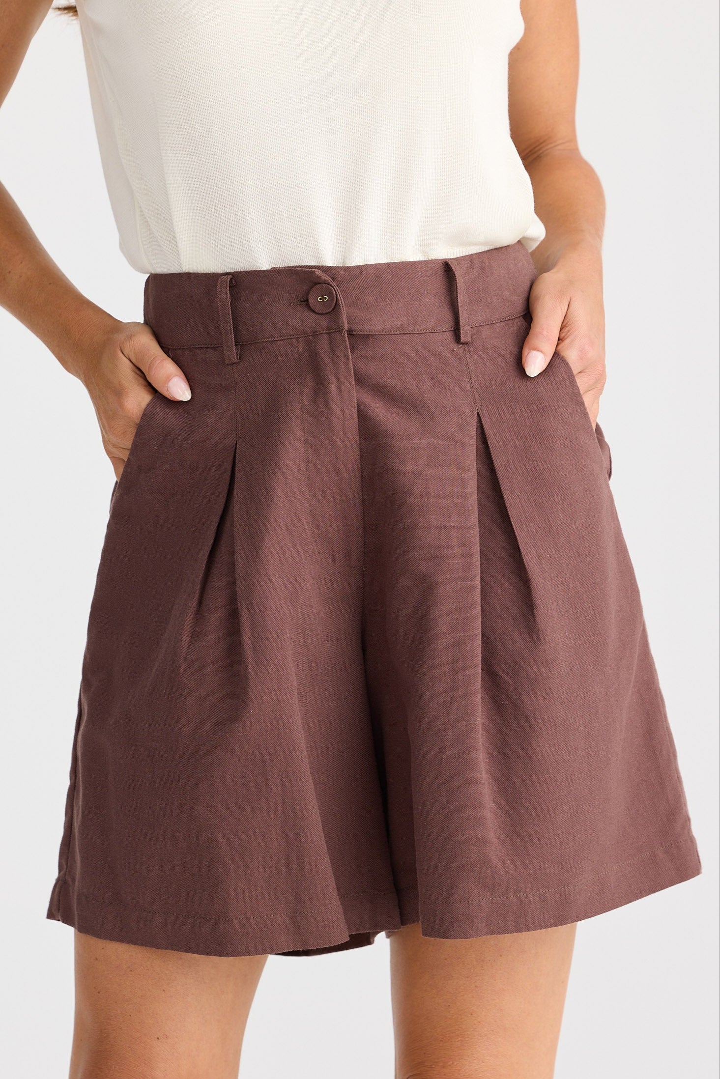 Brown shorts worn by a person on a white background