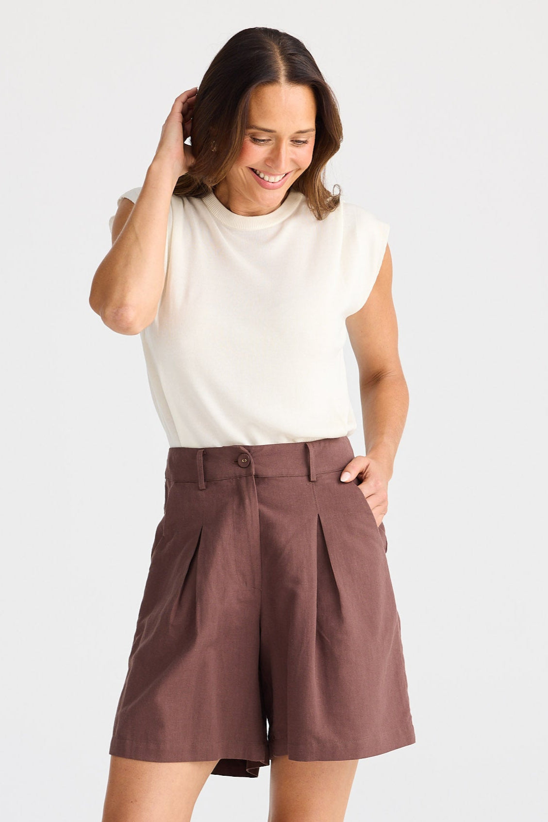 Woman wearing brown shorts and a white top on a white background
