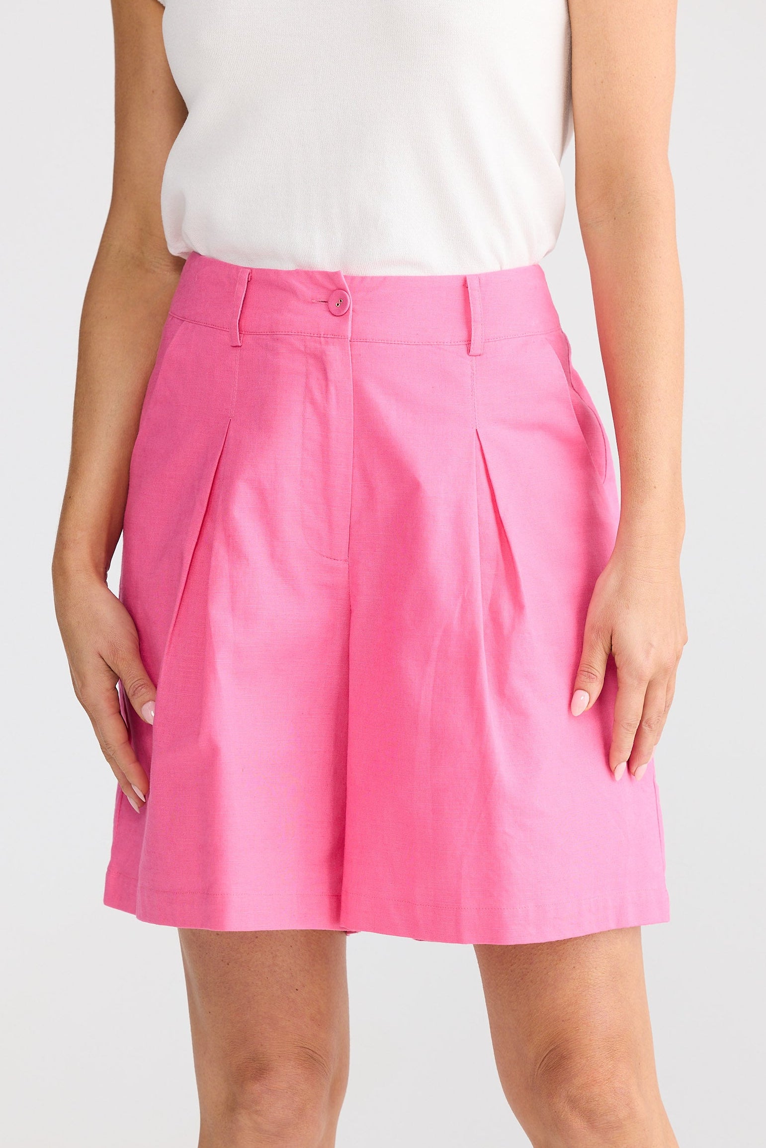 Person wearing a pink shorts and white top on a white background