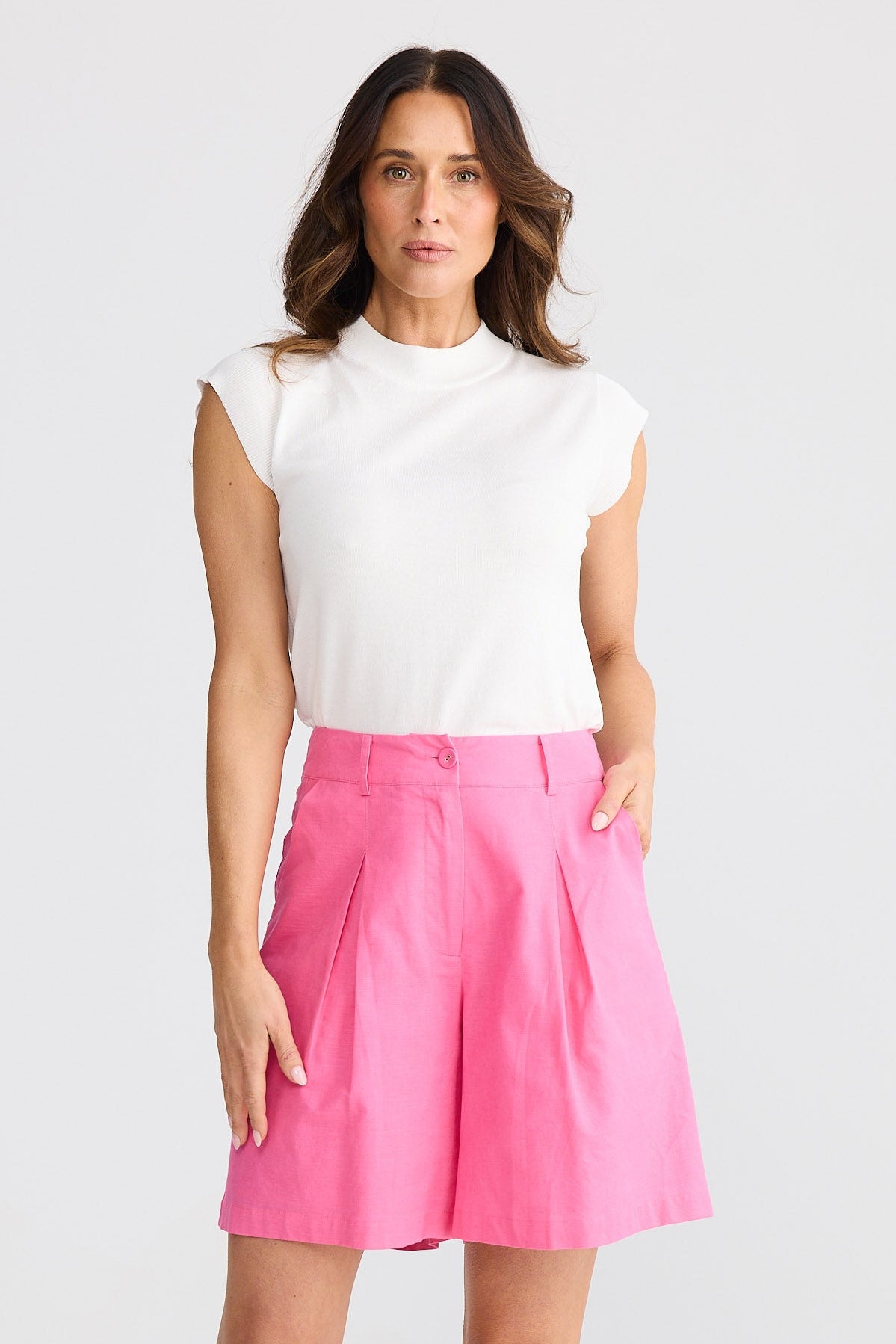 Woman wearing a white top and pink shorts on a white background