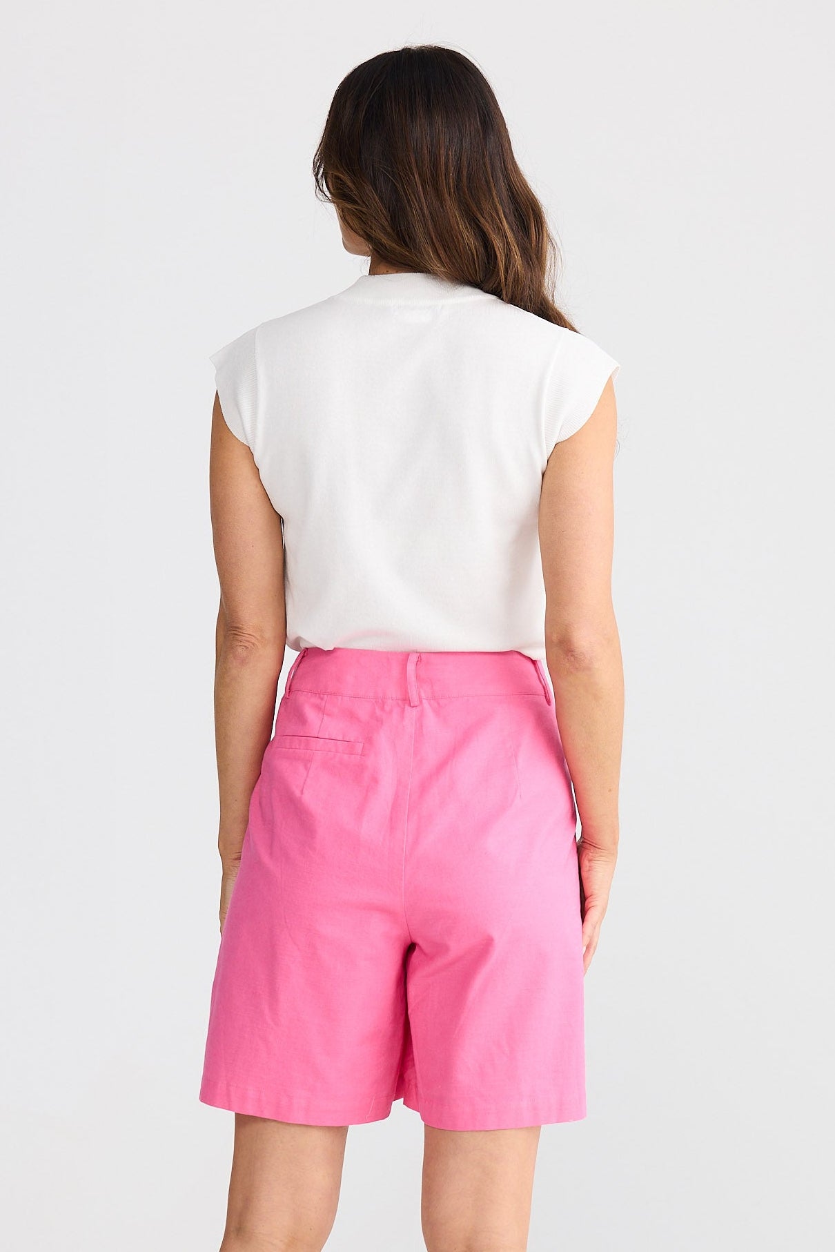 Woman wearing a white top and pink shorts on a white background