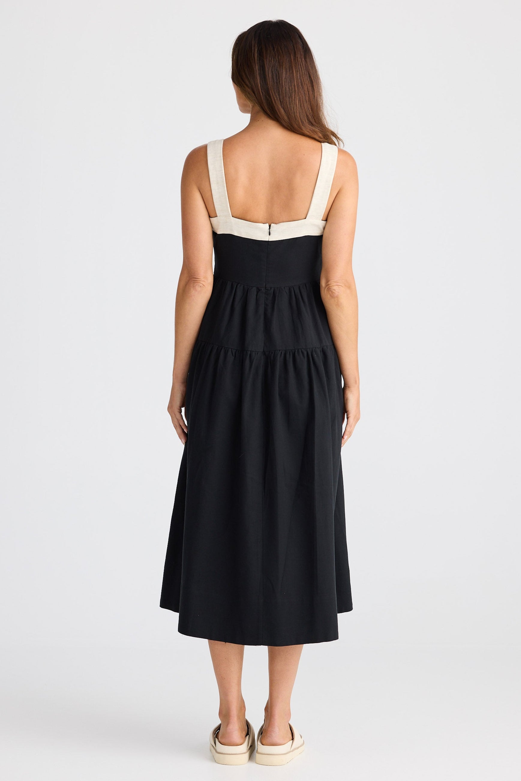 Woman wearing a black dress with a white strap on a white background