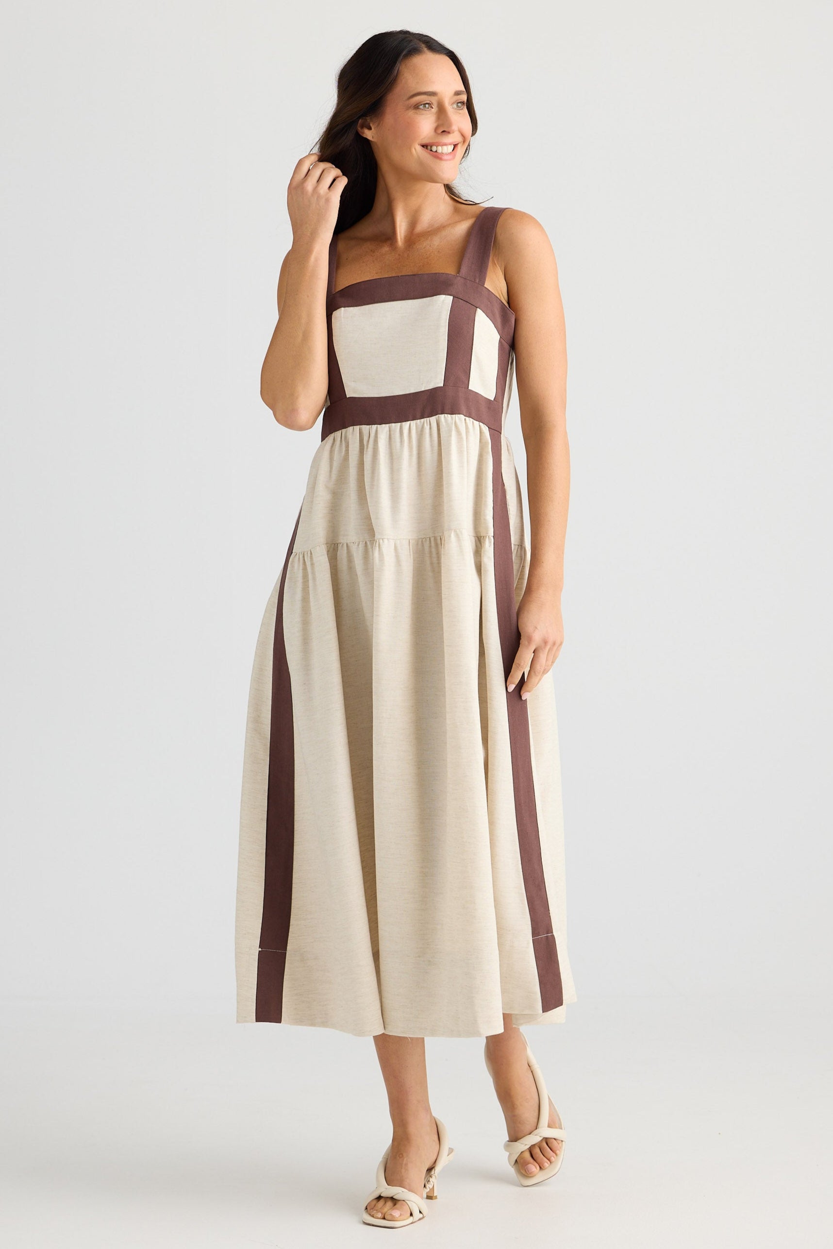 Woman wearing a beige and brown dress on a white background
