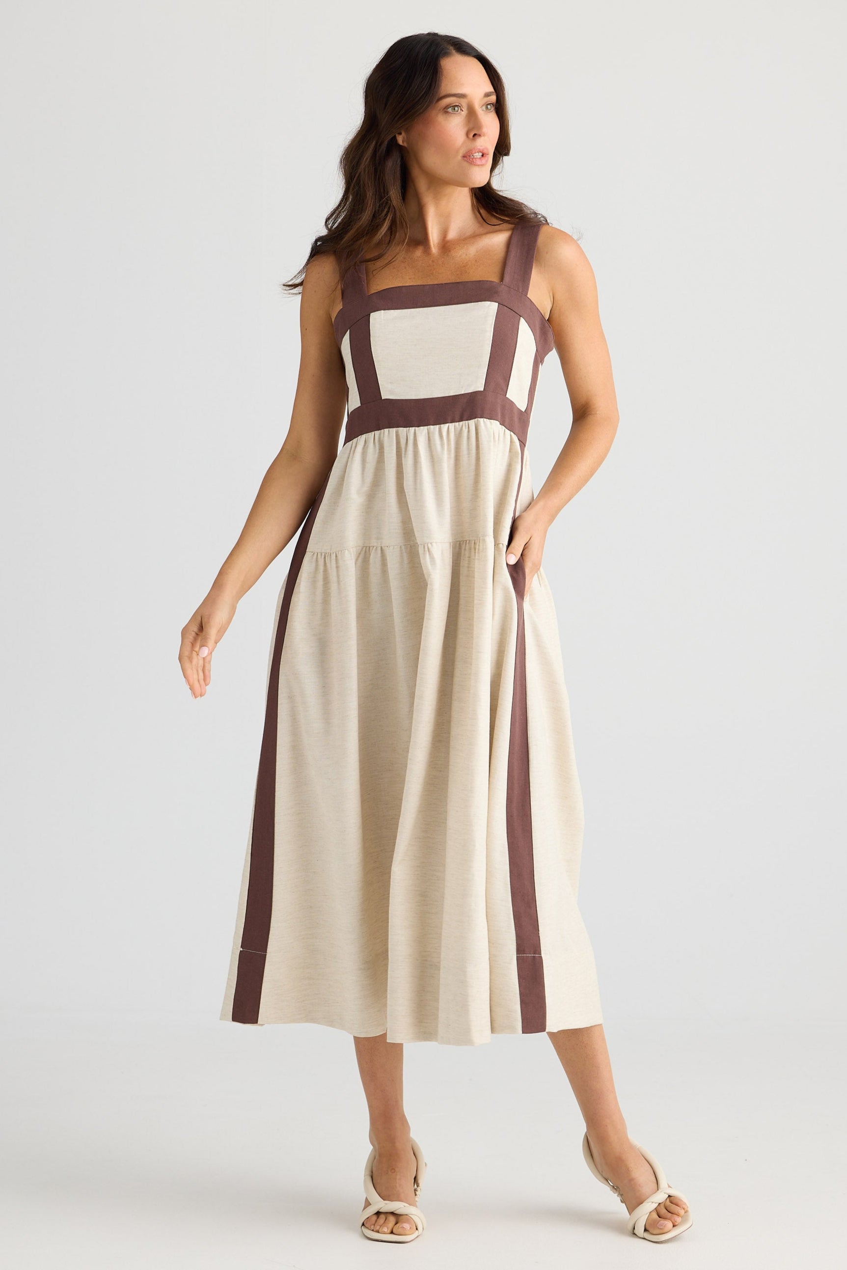 Woman wearing a beige and brown dress on a white background