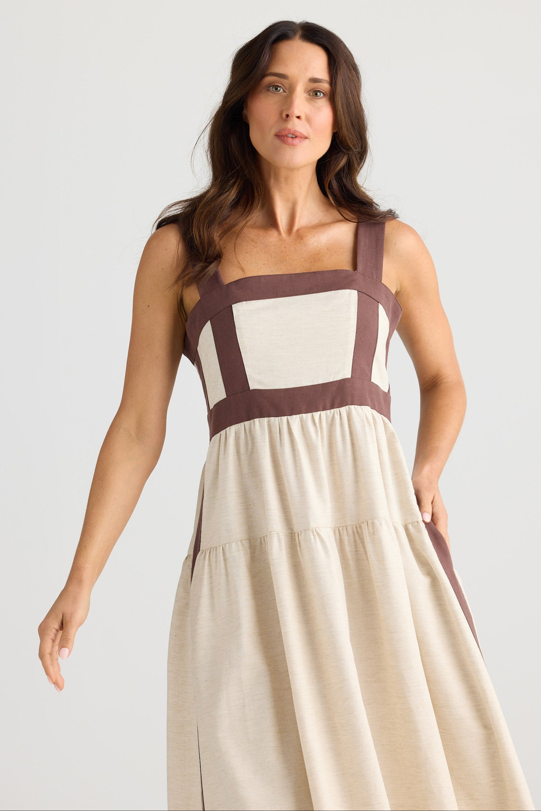 Woman wearing a beige dress with brown straps against a white background