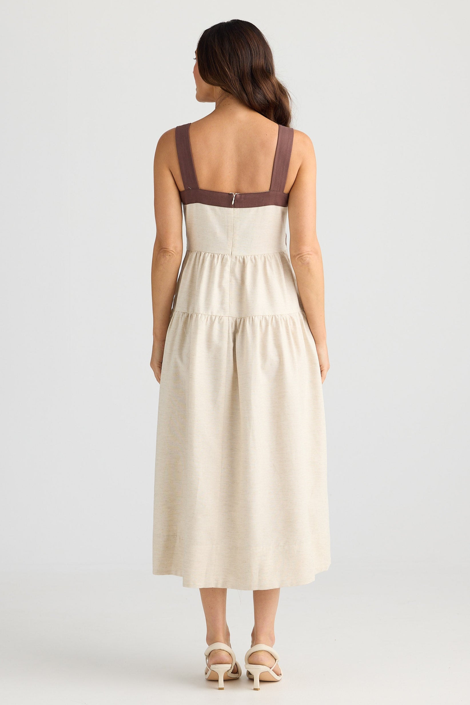 Woman wearing a beige dress with brown straps on a white background